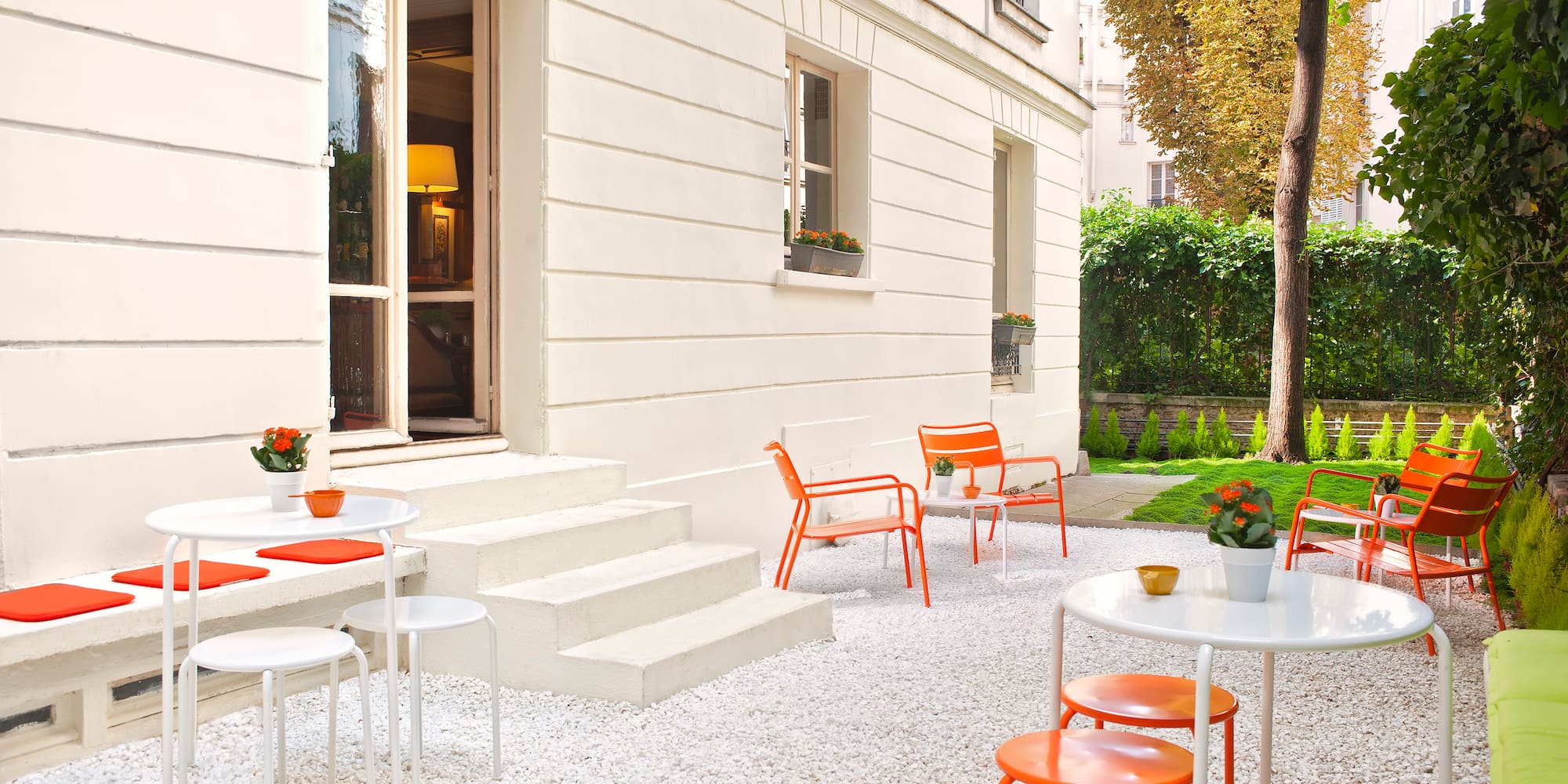 a white building with orange chairs and tables