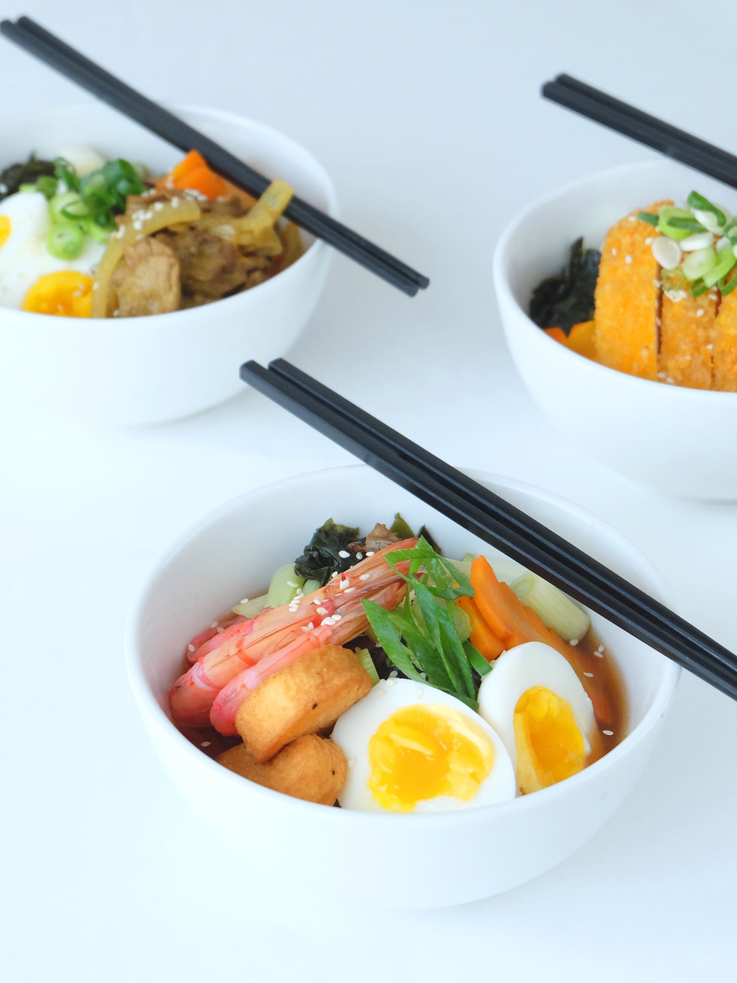 a group of bowls of food with chopsticks
