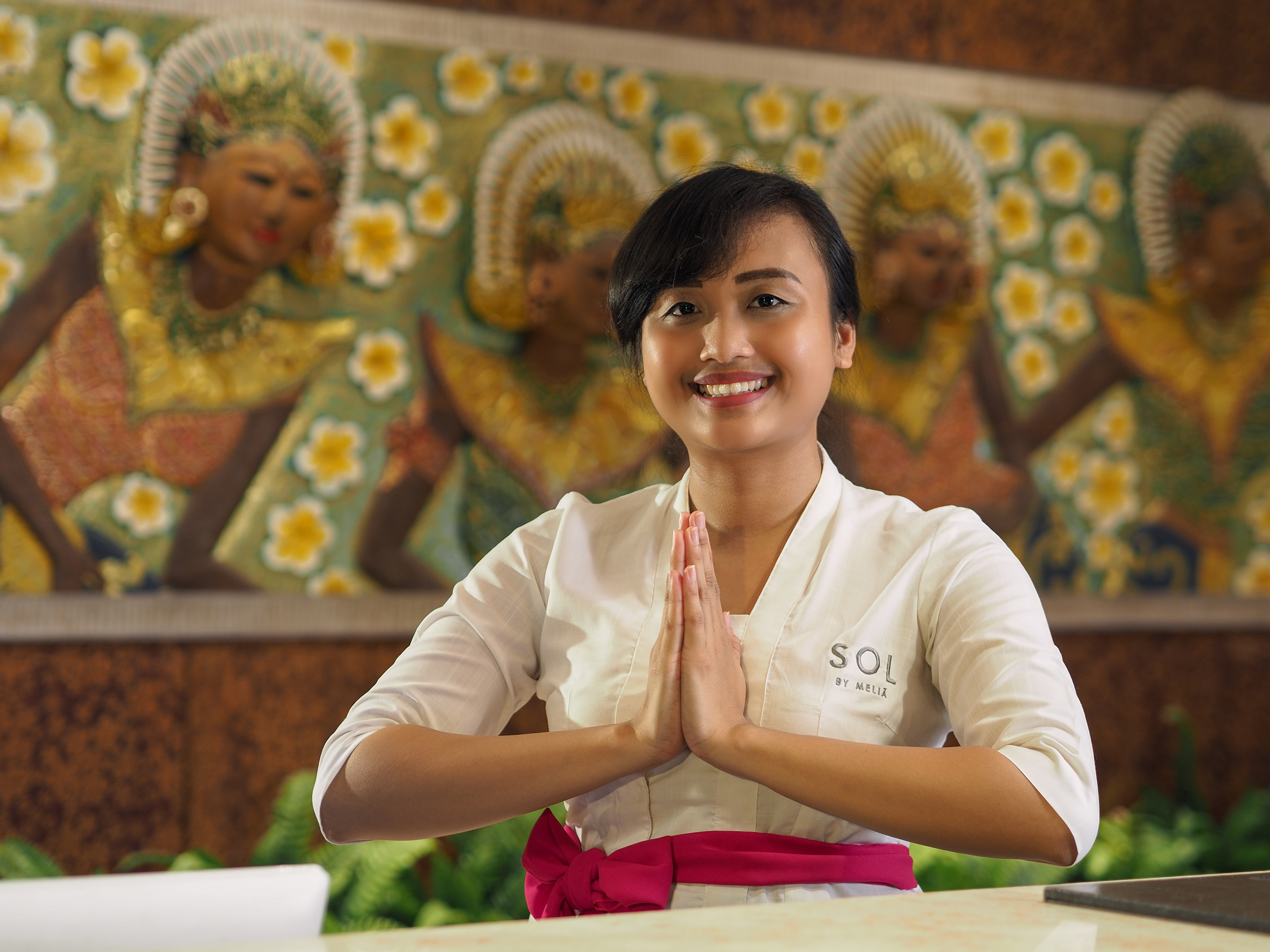 a woman with hands together in front of a desk