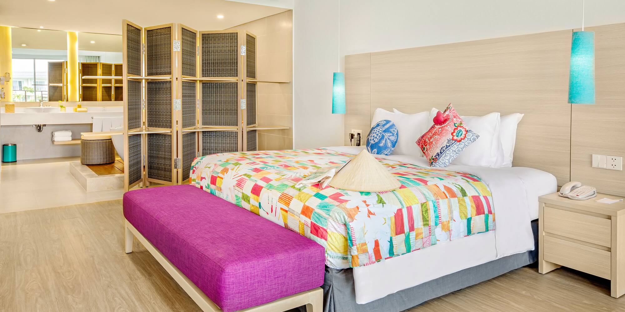 a bed with colorful blankets and a purple bench