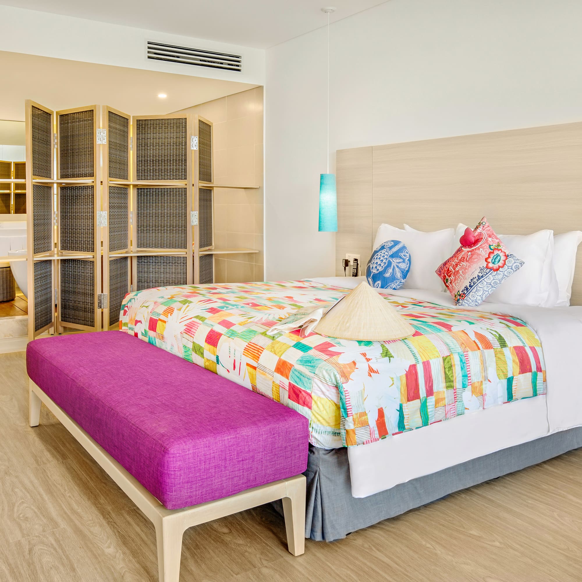 a bed with colorful blankets and a purple bench