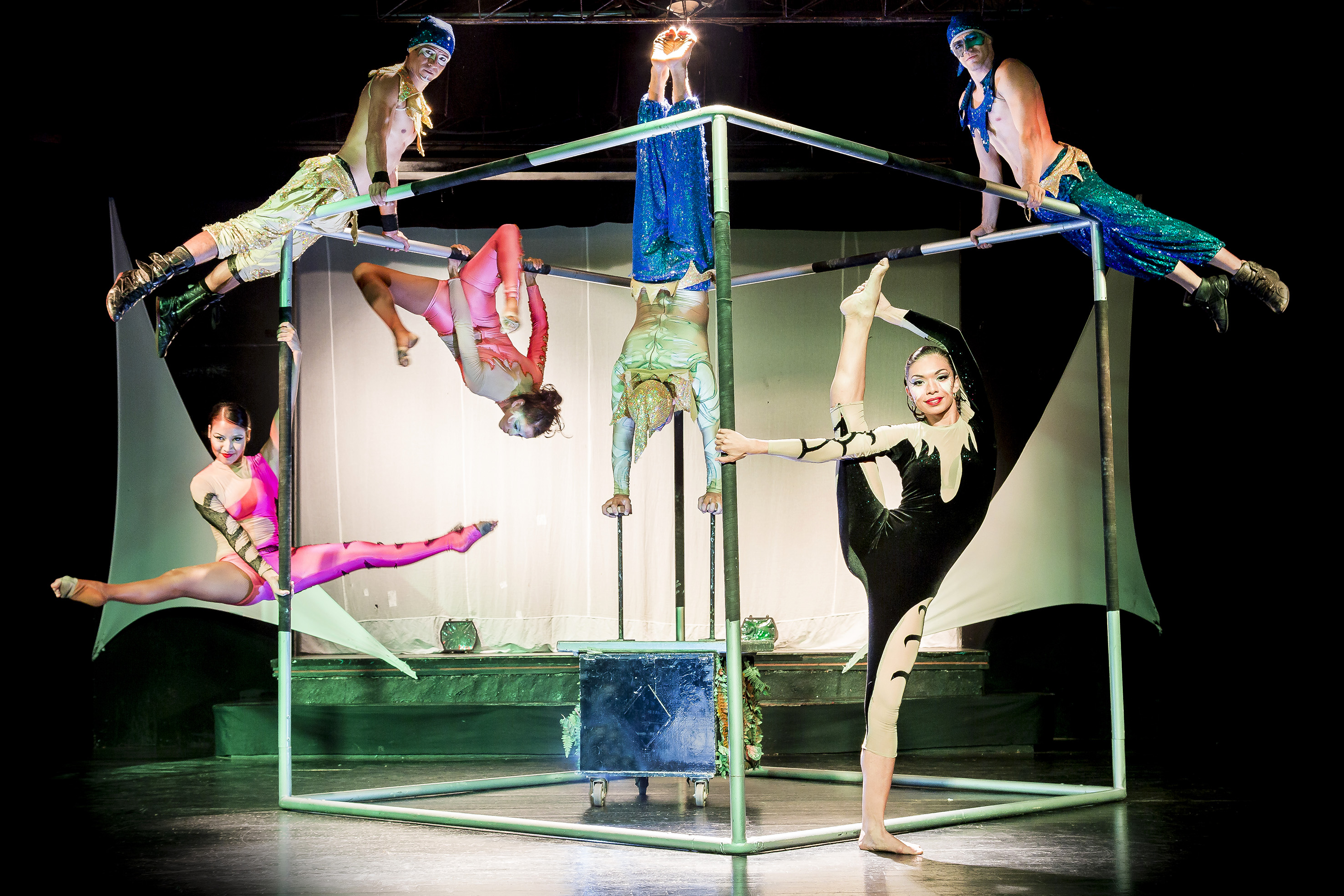 Colorful circus acrobats performing balancing acts on a metal stage frame.