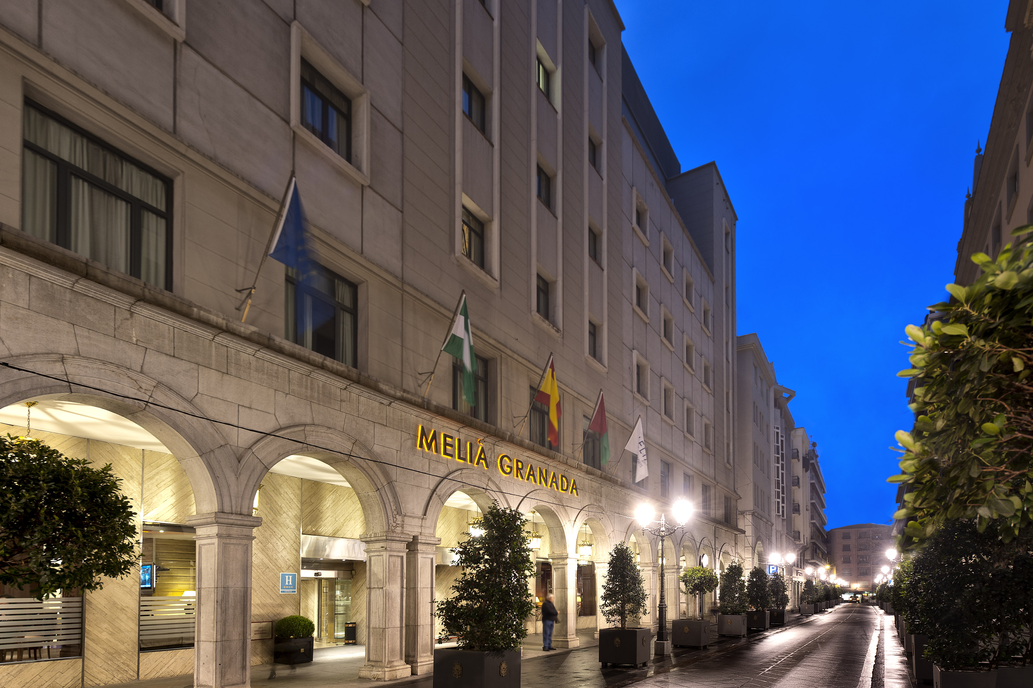 Meliá Granada hotel exterior at night, illuminated sign, arches, flags.
