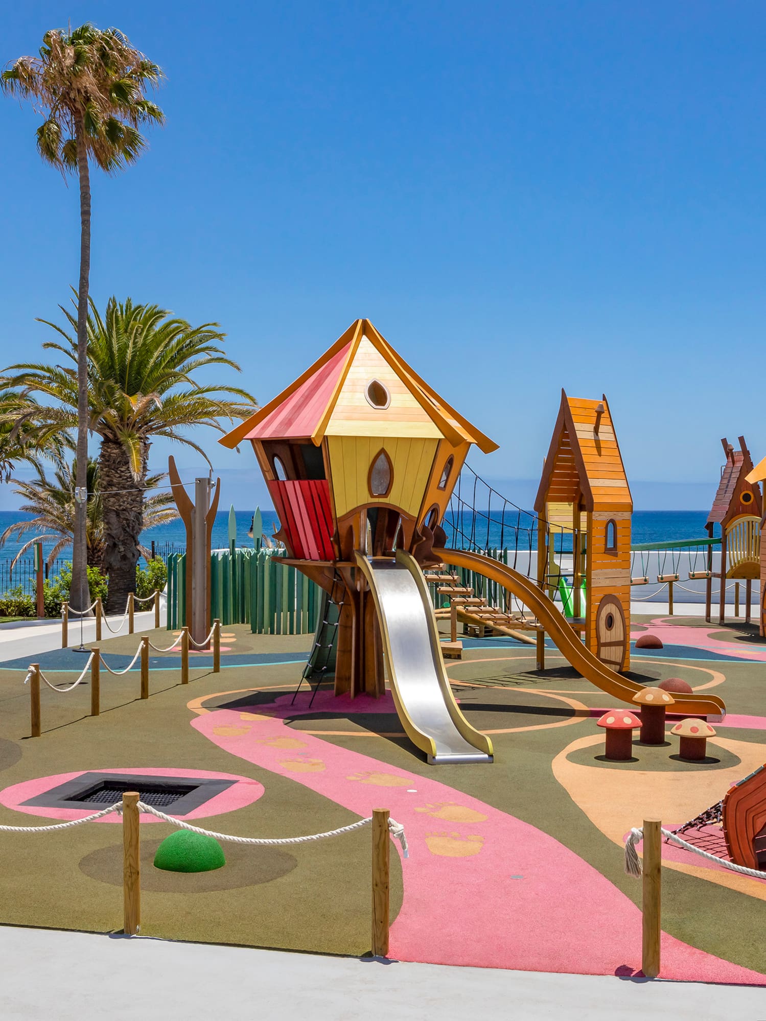 a playground with a slide and a beach in the background