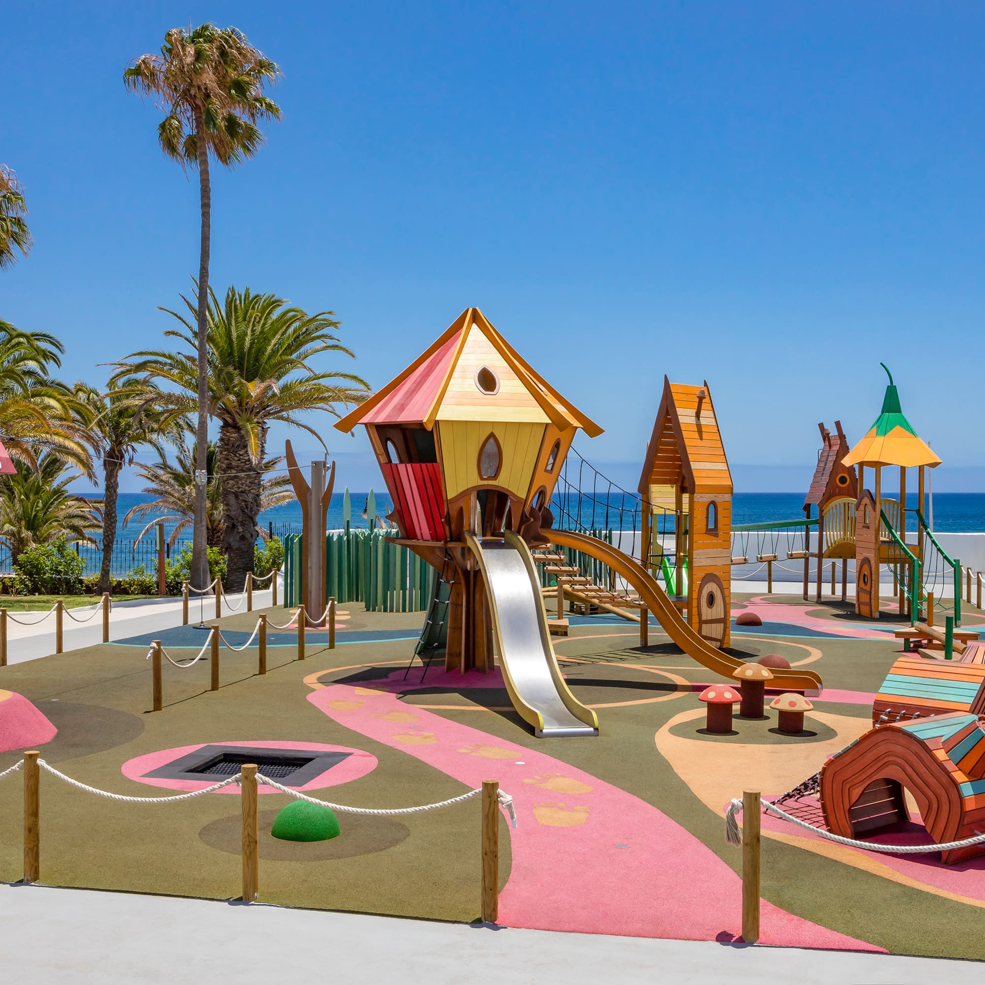 a playground with a slide and a beach in the background