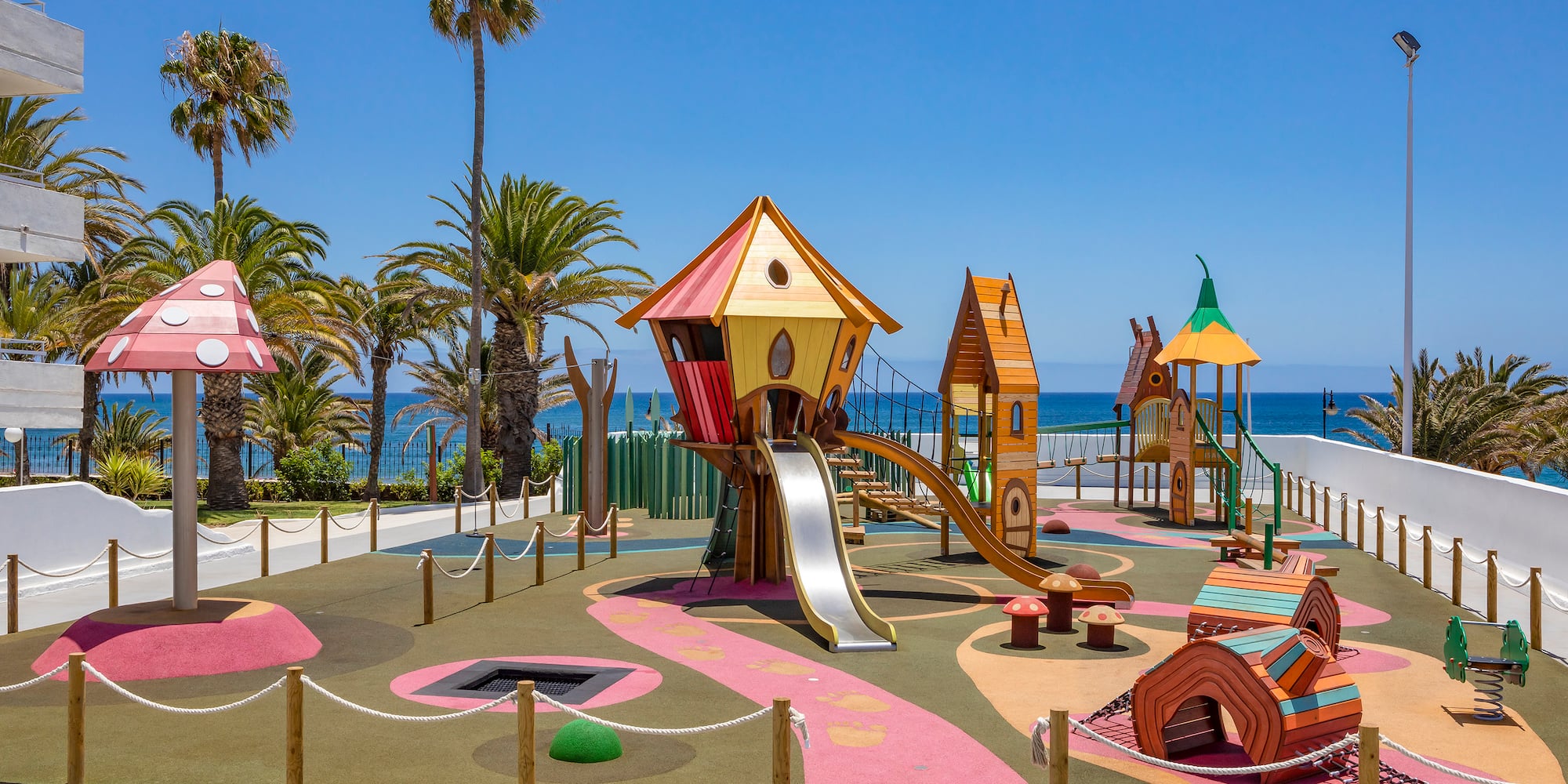a playground with a slide and a beach in the background