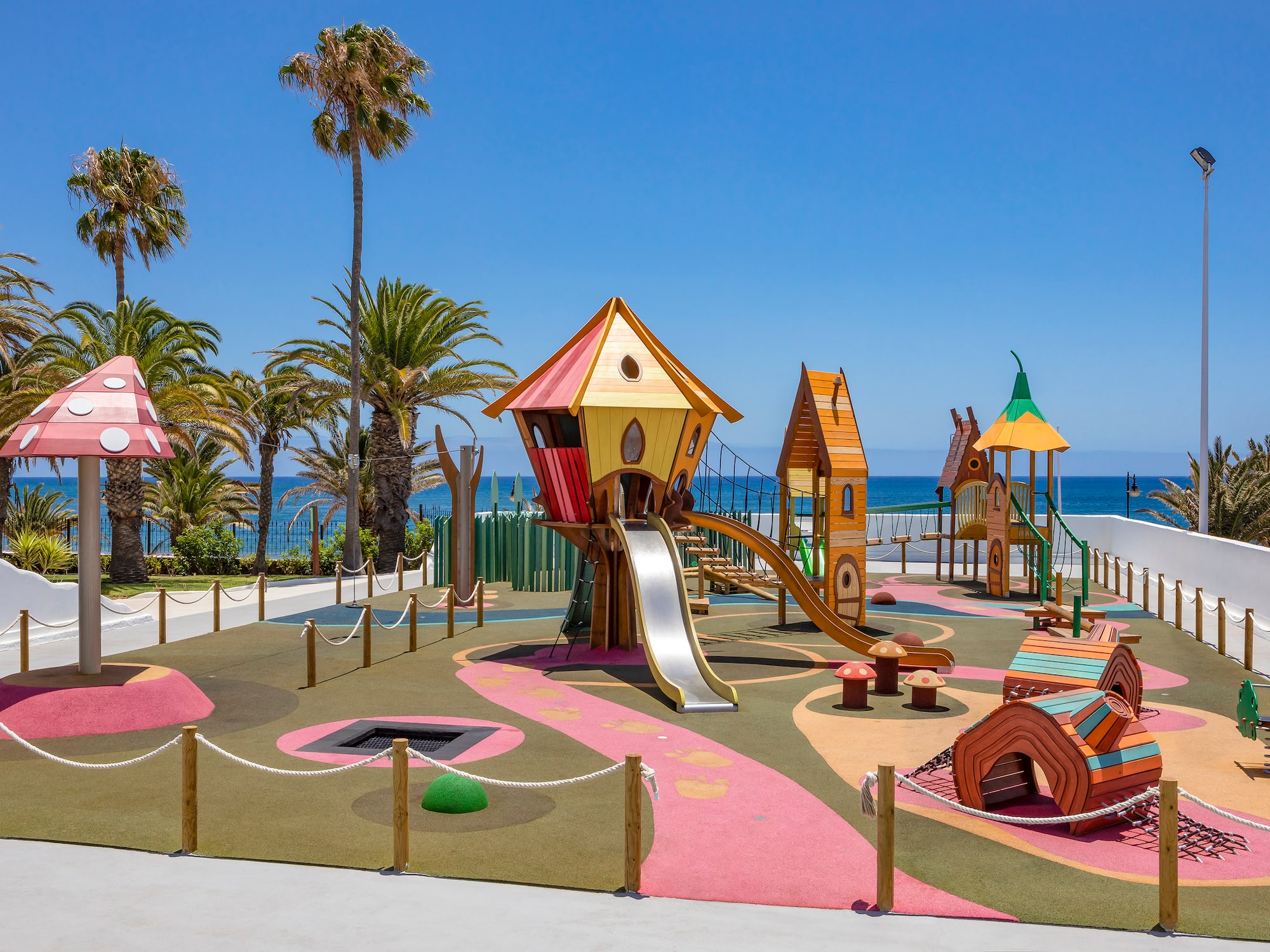 a playground with a slide and a beach in the background