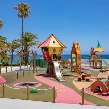 a playground with a slide and a beach in the background
