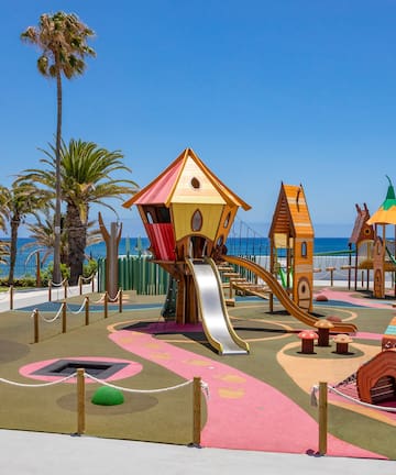 a playground with a slide and a beach in the background