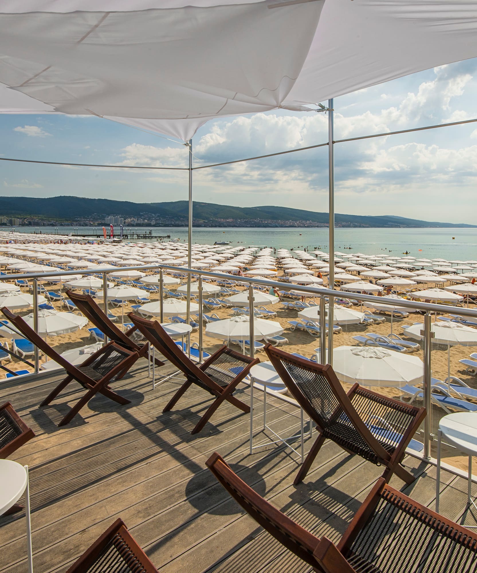 a deck with chairs and umbrellas on a beach