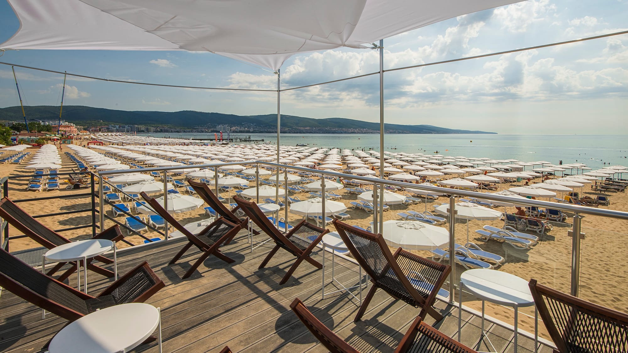 a deck with chairs and umbrellas on a beach