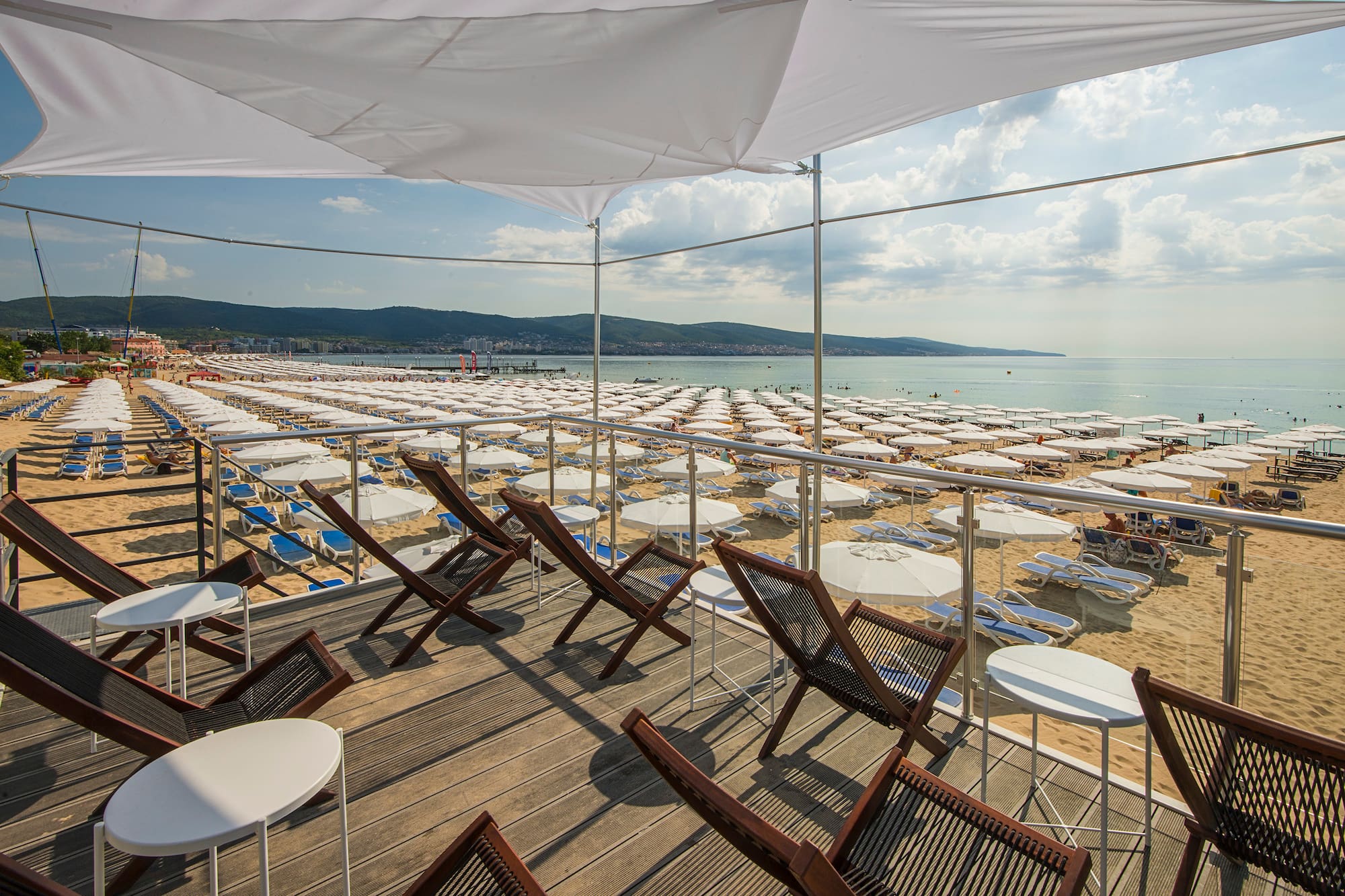 a deck with chairs and umbrellas on a beach