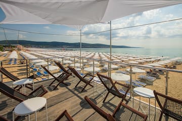 a deck with chairs and umbrellas on a beach