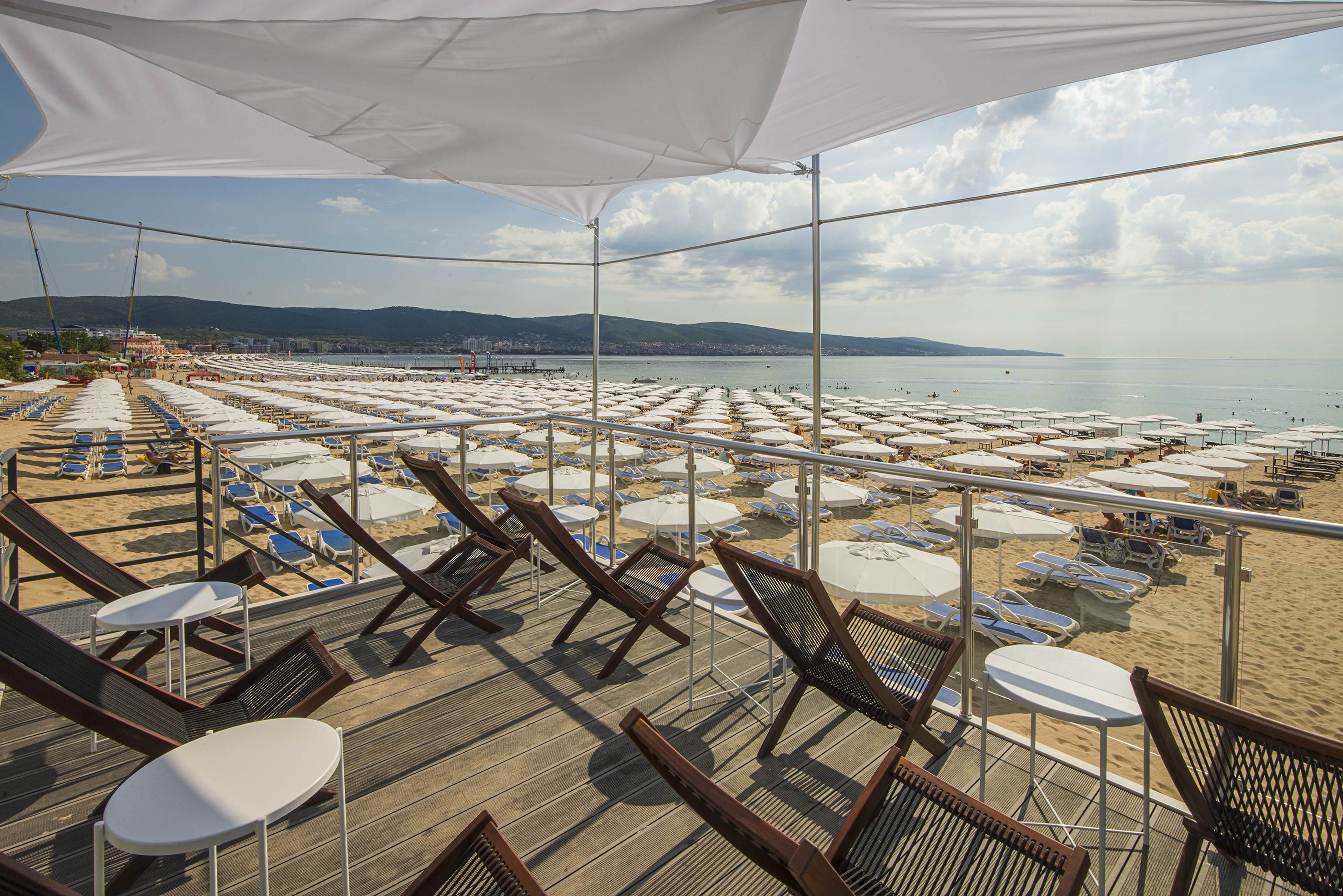 a deck with chairs and umbrellas on a beach