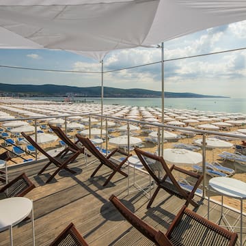 a deck with chairs and umbrellas on a beach