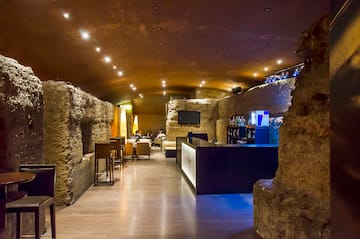 a room with a stone wall and tables and chairs