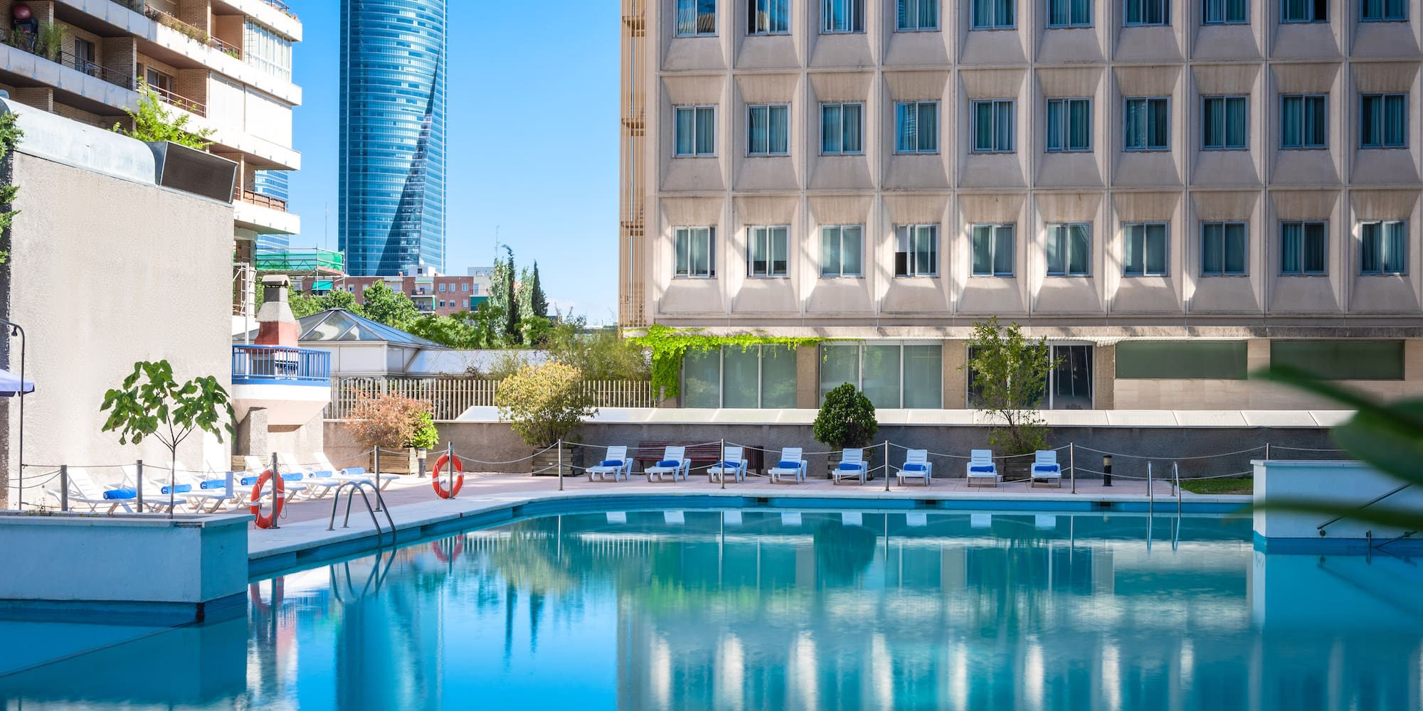 a pool with chairs and a building in the background