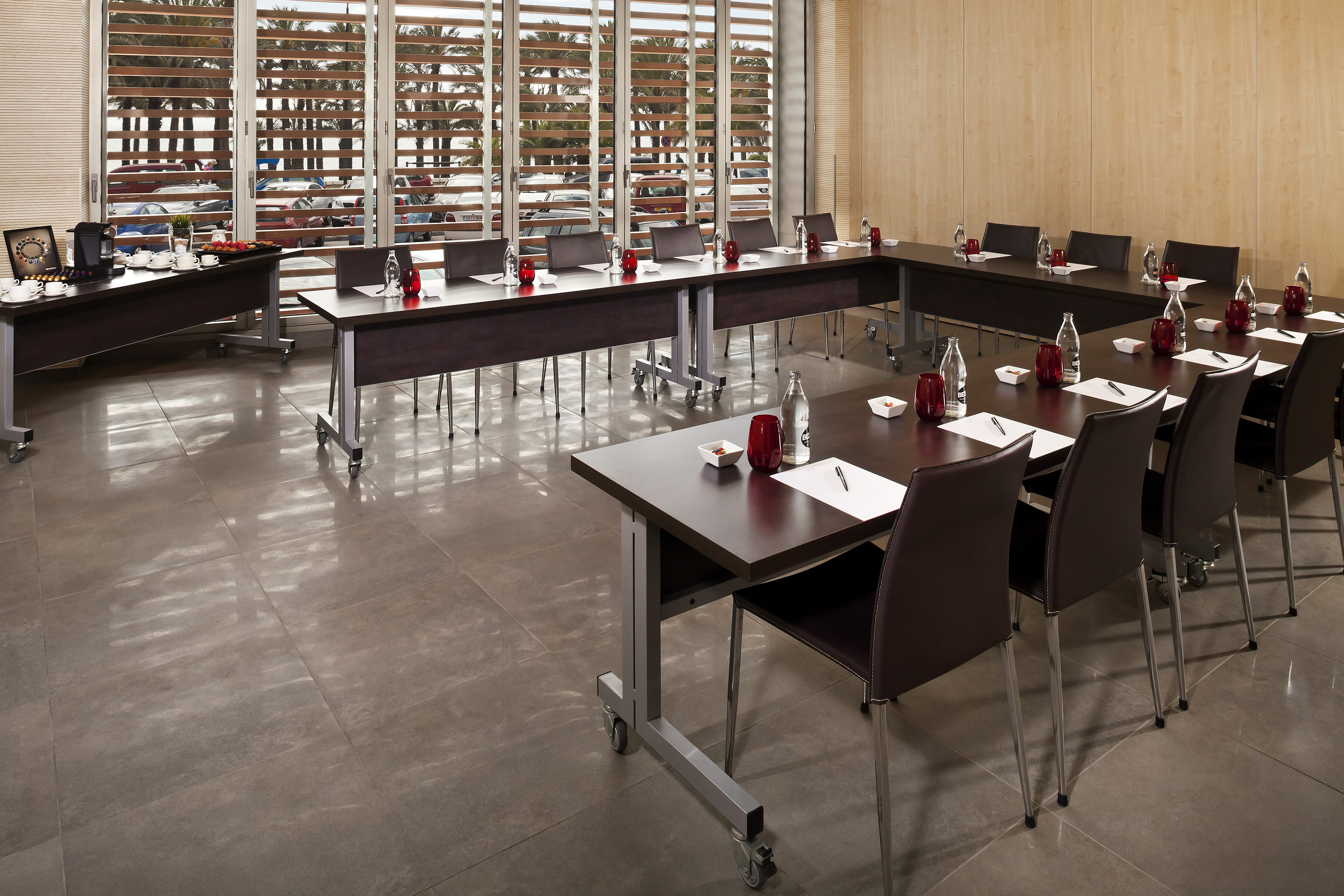 Modern U-shape meeting room with dark tables, brown chairs, and refreshments.