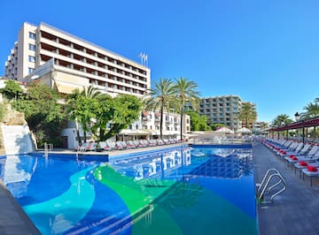 a pool with chairs and trees in front of a building