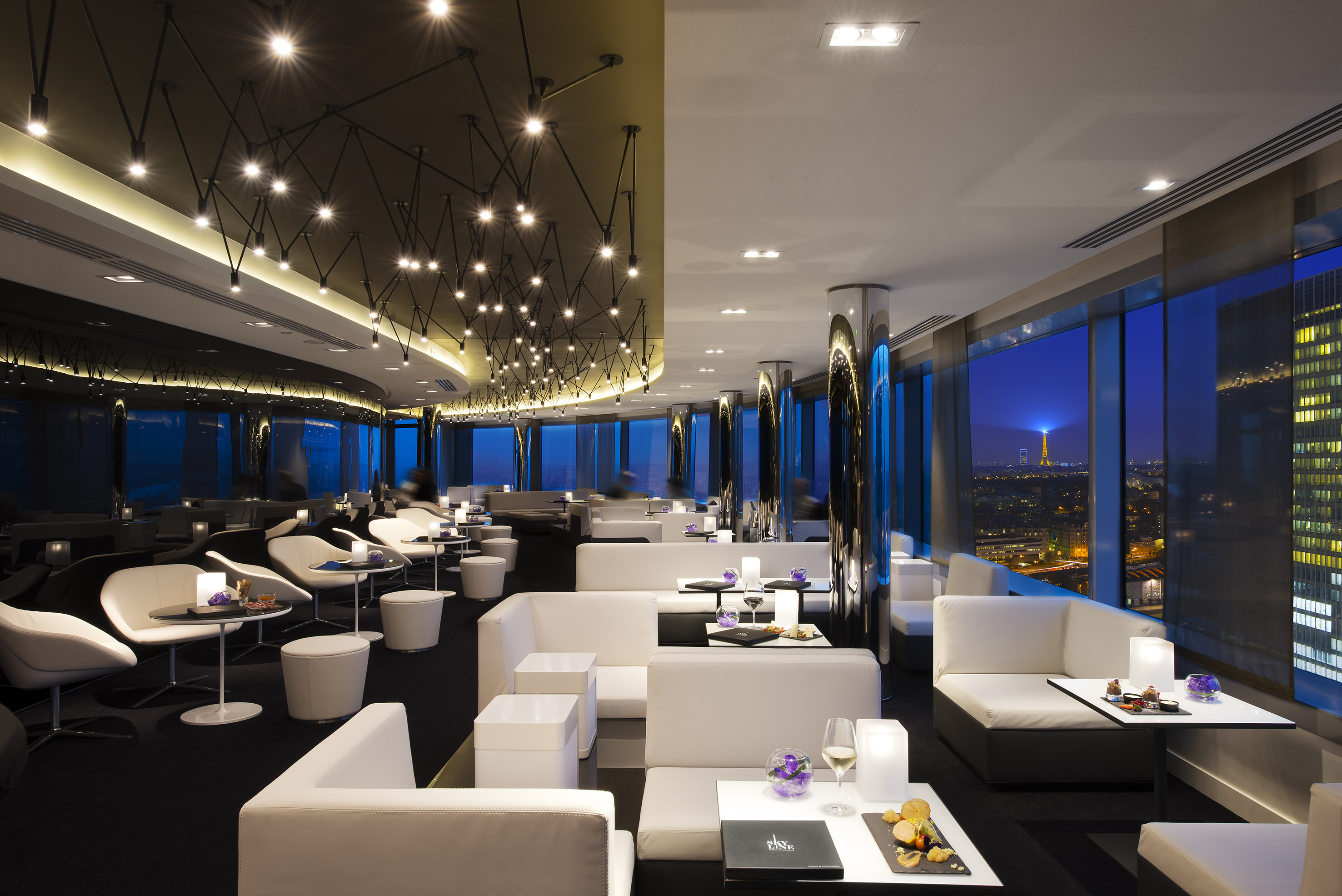 Elegant bar interior, white furniture, Paris city view with Eiffel Tower.