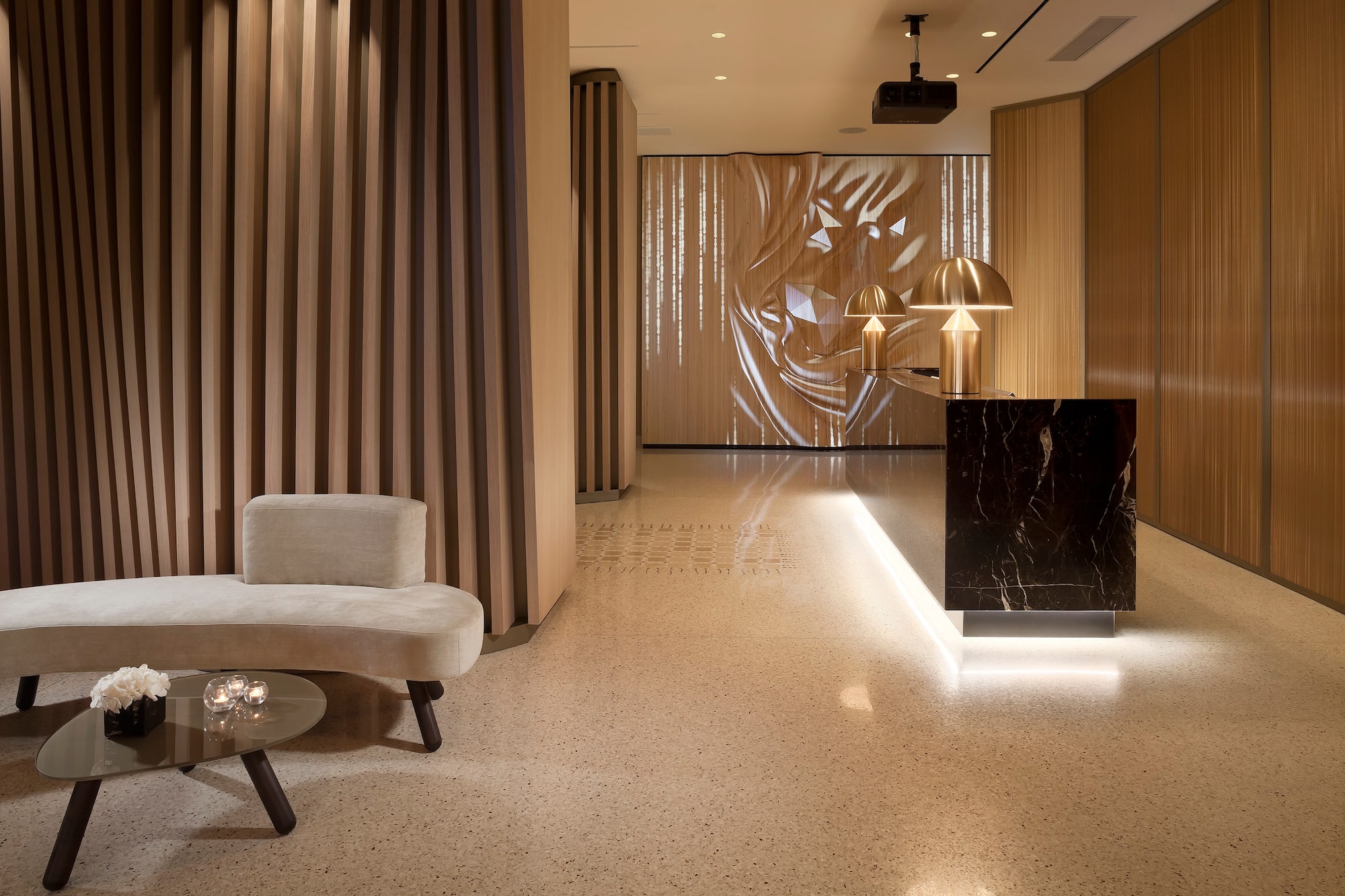 Modern hotel lobby with marble reception, gold lamps, wood panels, and lounge.