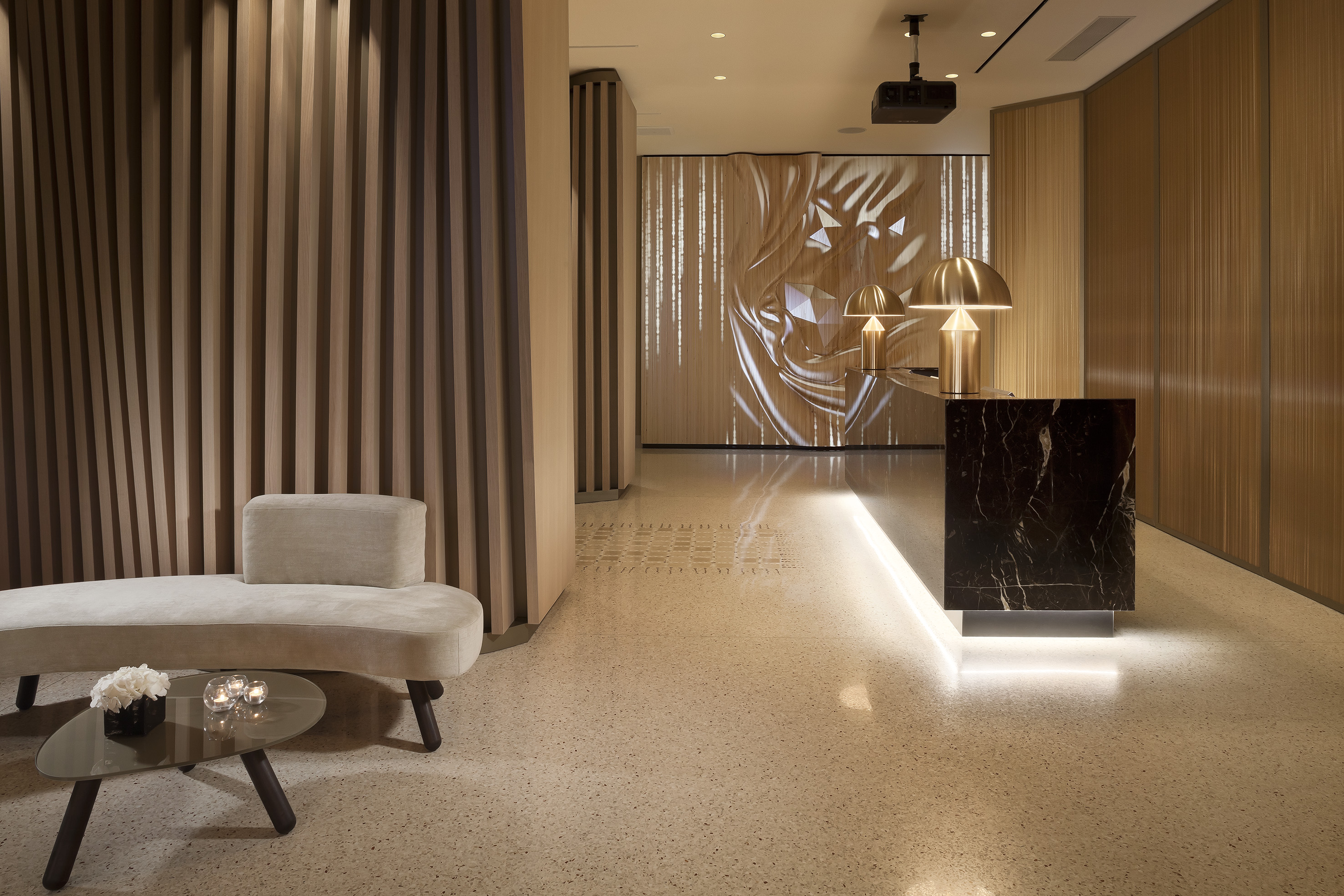 Modern hotel lobby with marble reception, gold lamps, wood panels, and lounge.