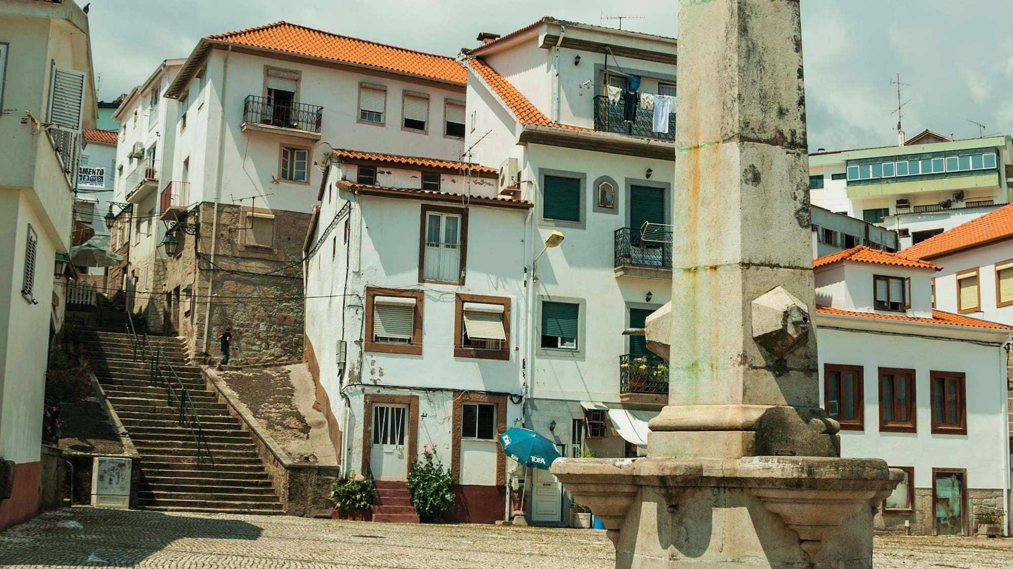 a stone pillar in a courtyard with buildings in the background