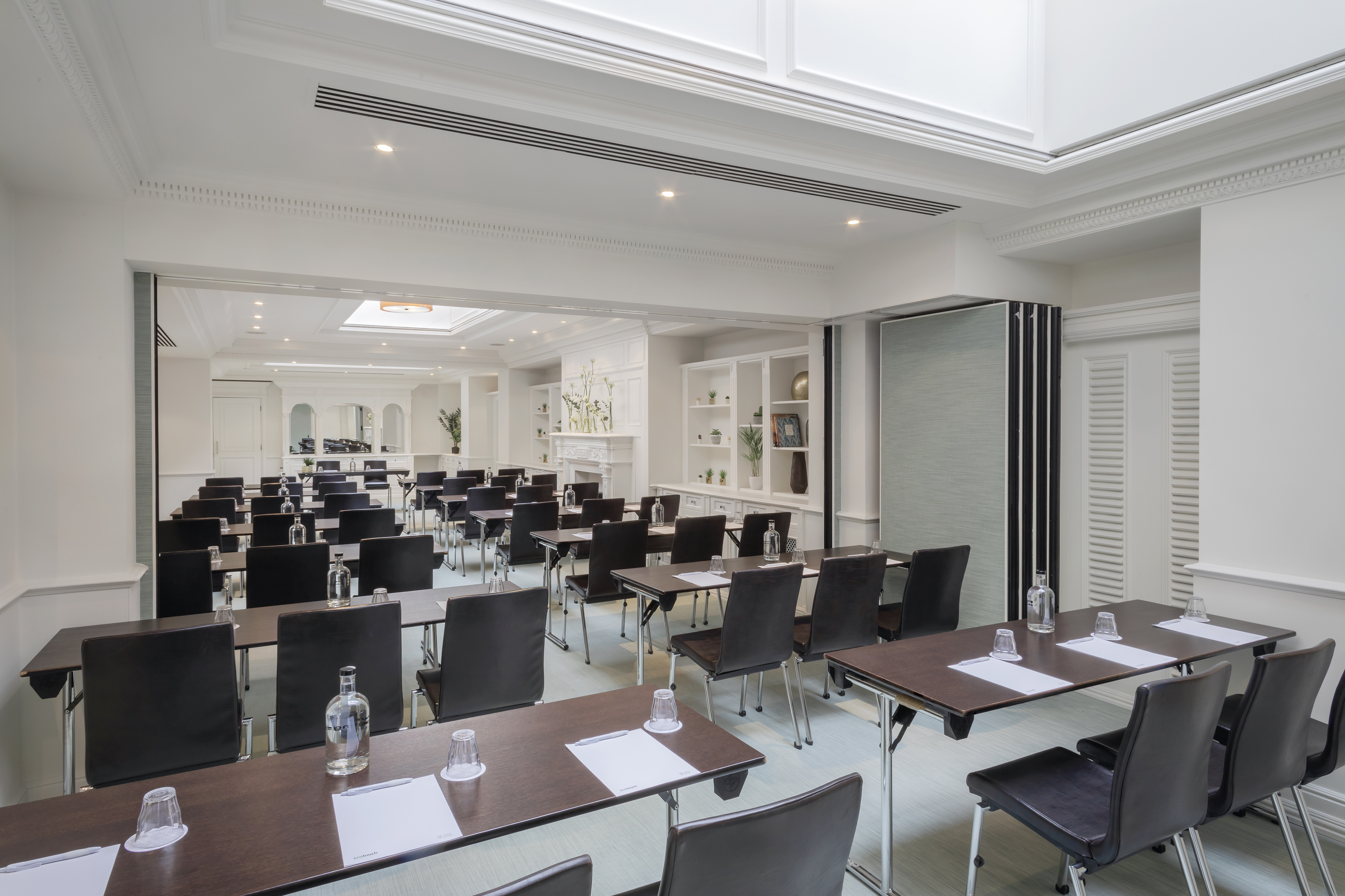 Modern meeting room with classroom setup, tables, chairs, and white decor.