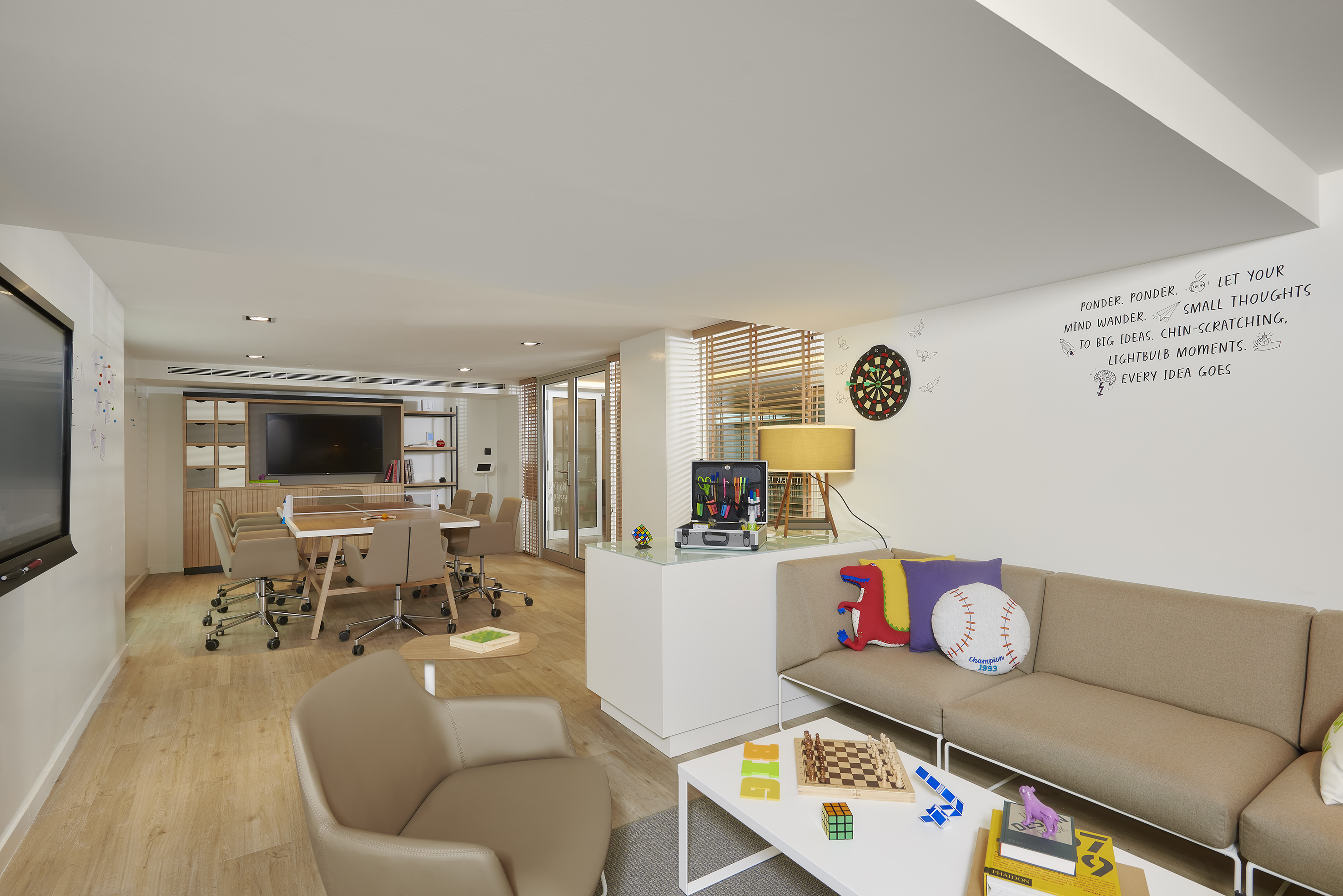 Modern creative office with meeting area, lounge, games, and inspirational wall art.