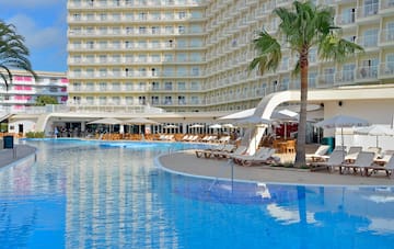a pool with lounge chairs and umbrellas in front of a large building