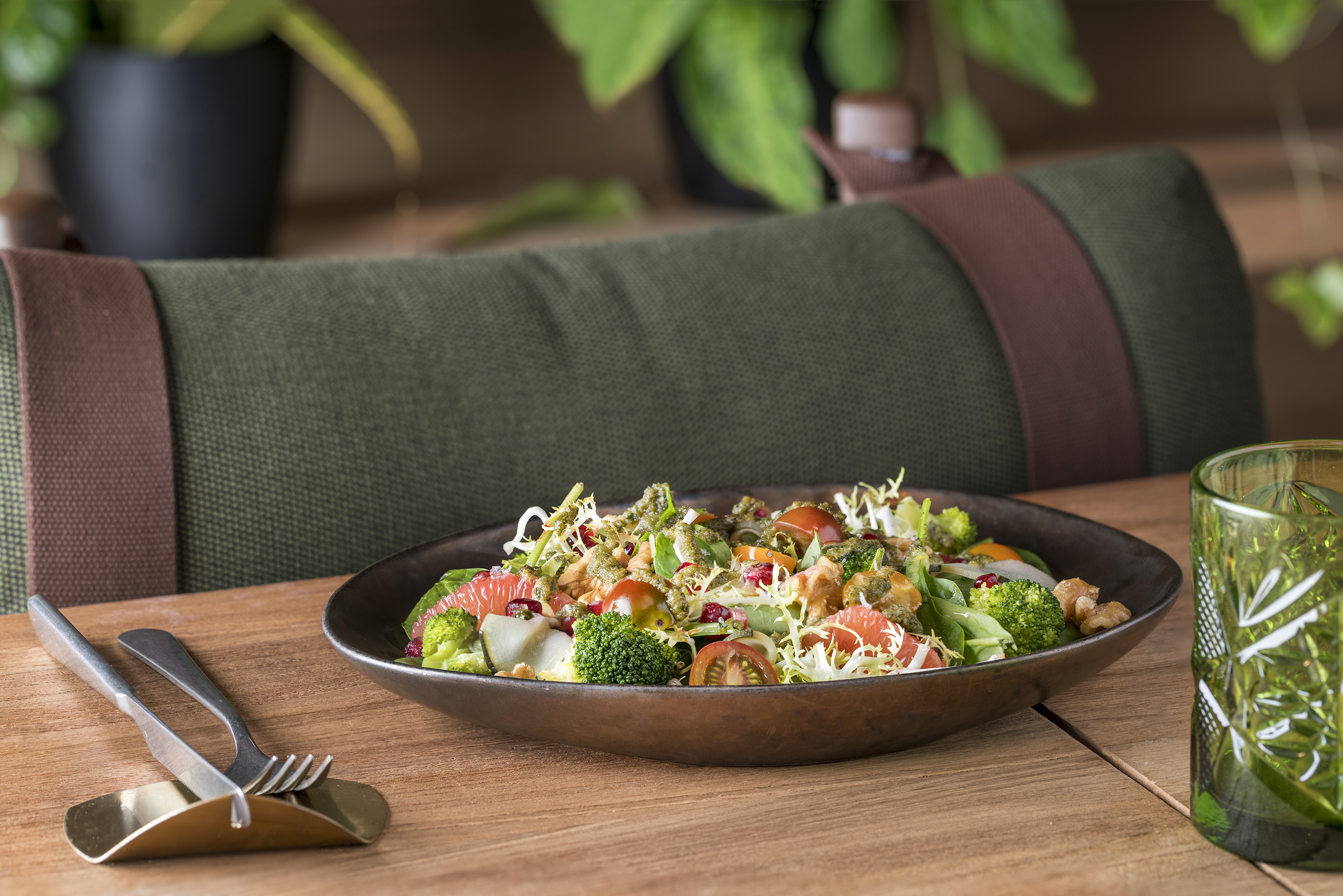 Vibrant fresh salad with broccoli, grapefruit, tomatoes, greens, on wooden table.