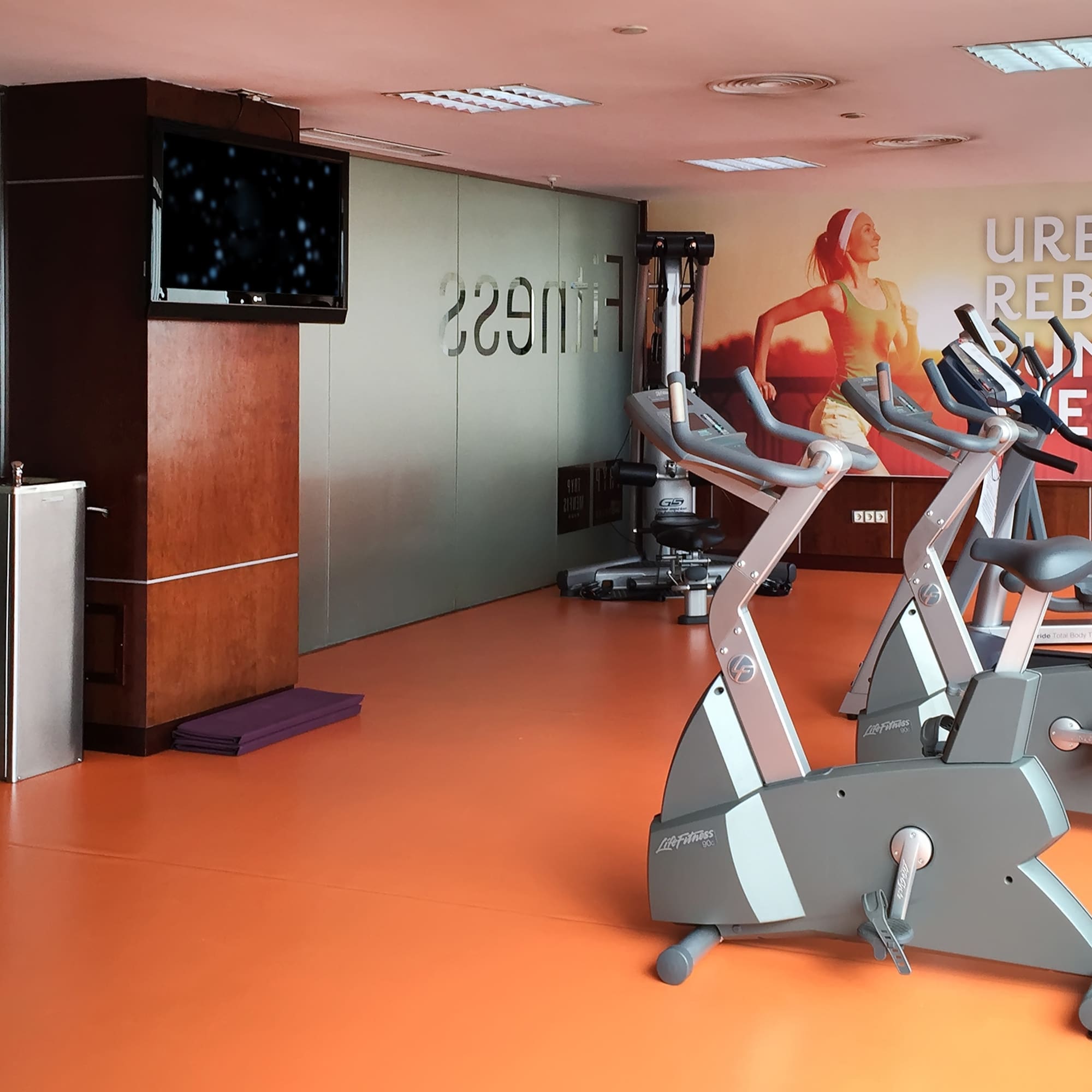 a room with exercise bikes and a tv