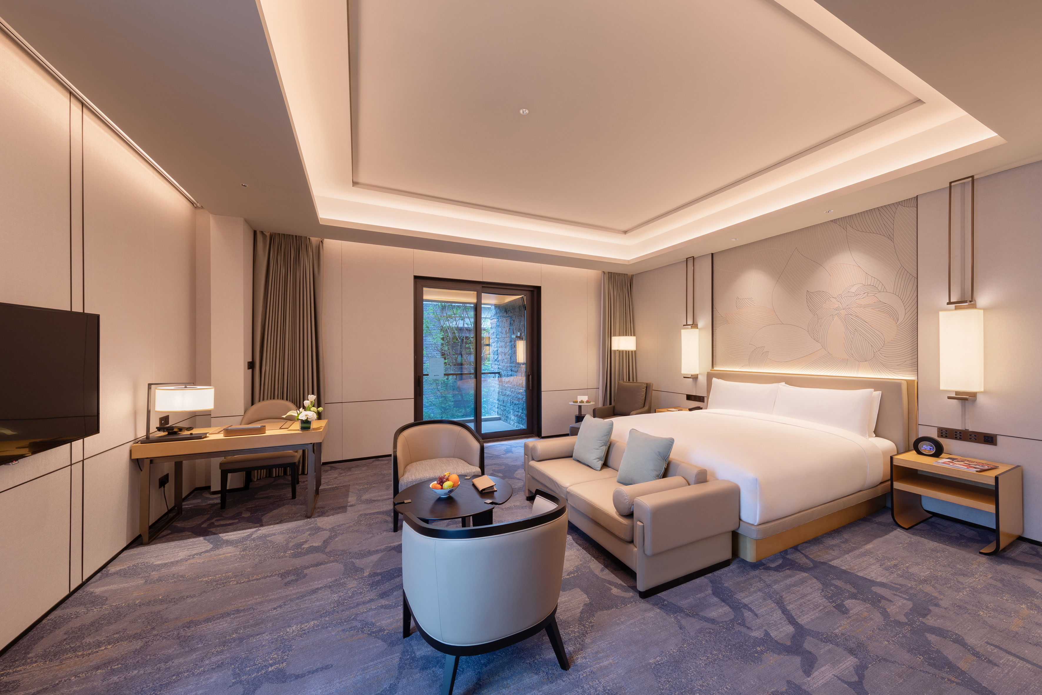 Modern luxury hotel suite with king bed, living area, and balcony access.