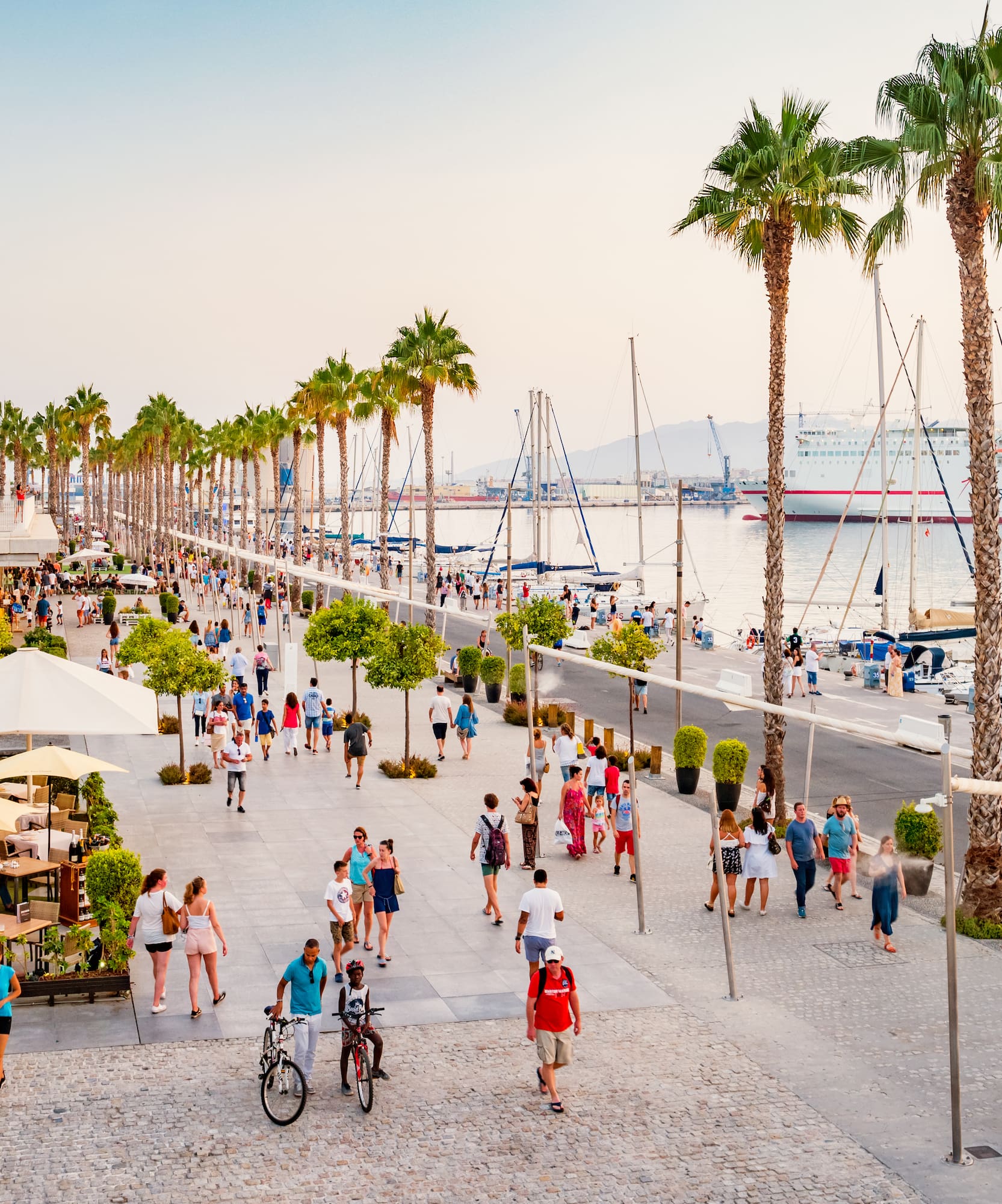 Muelle Uno Málaga: paseo con palmeras, gente, ferry y barcos en puerto.