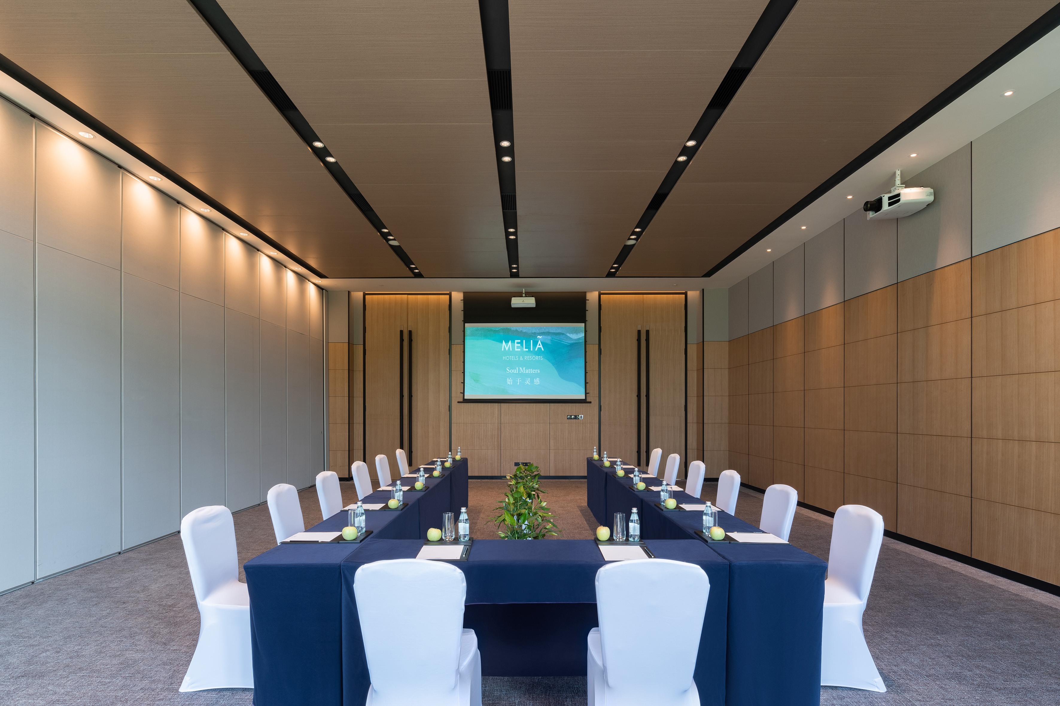 Professional Melia meeting room with U-shaped table, white chairs, and projector screen.