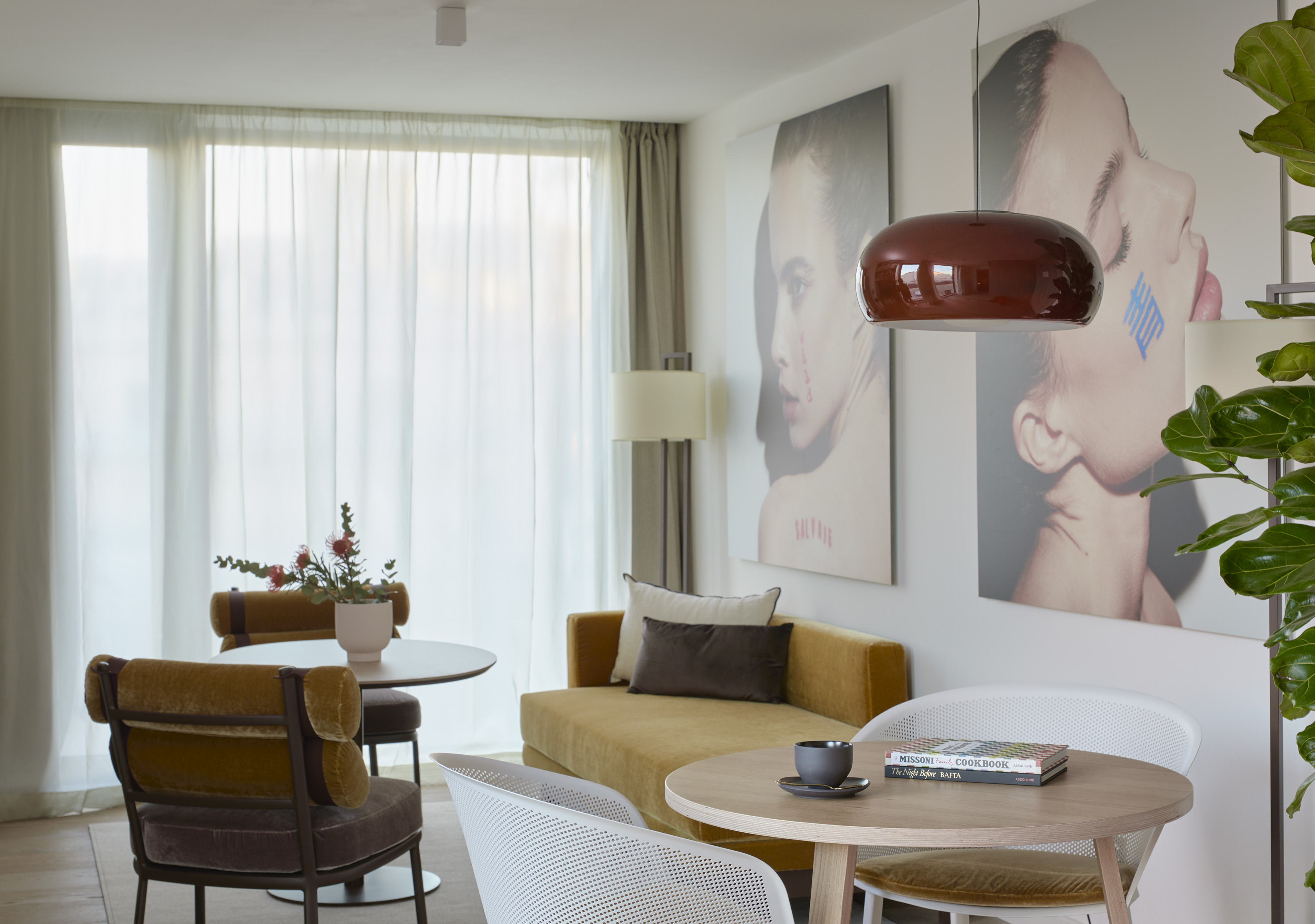 Modern living room with gold sofa, wood tables, and large abstract face art.