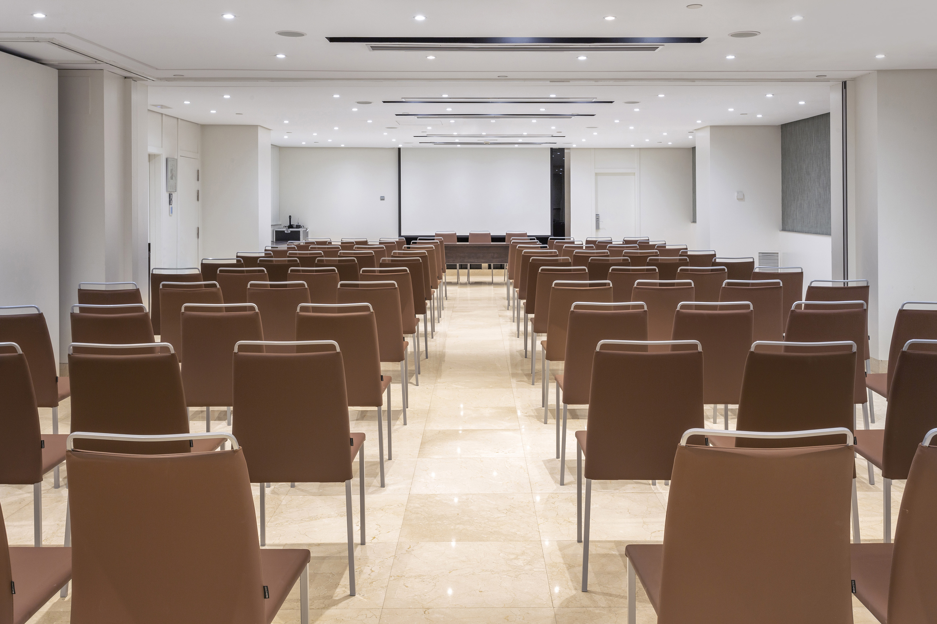 Empty conference room with brown seating and front projection screen for events.