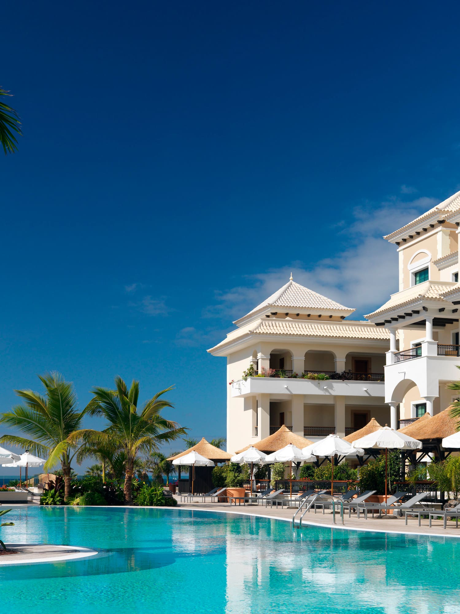 a pool with umbrellas and chairs in front of a building