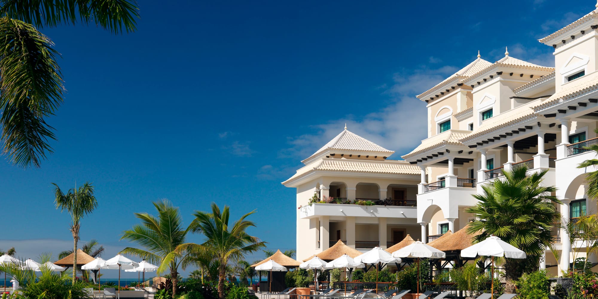 a pool with umbrellas and chairs in front of a building