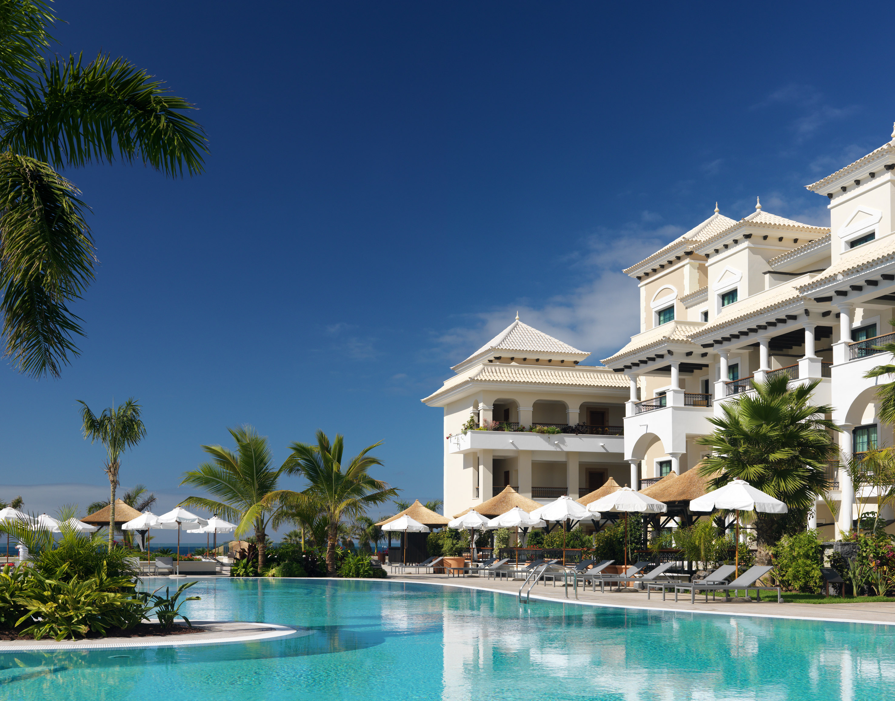 a pool with umbrellas and chairs in front of a building