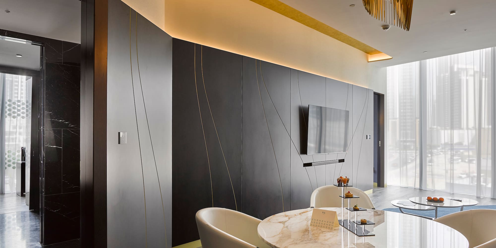 Sleek modern lounge with dark walls, gold accents, marble table, and city view.