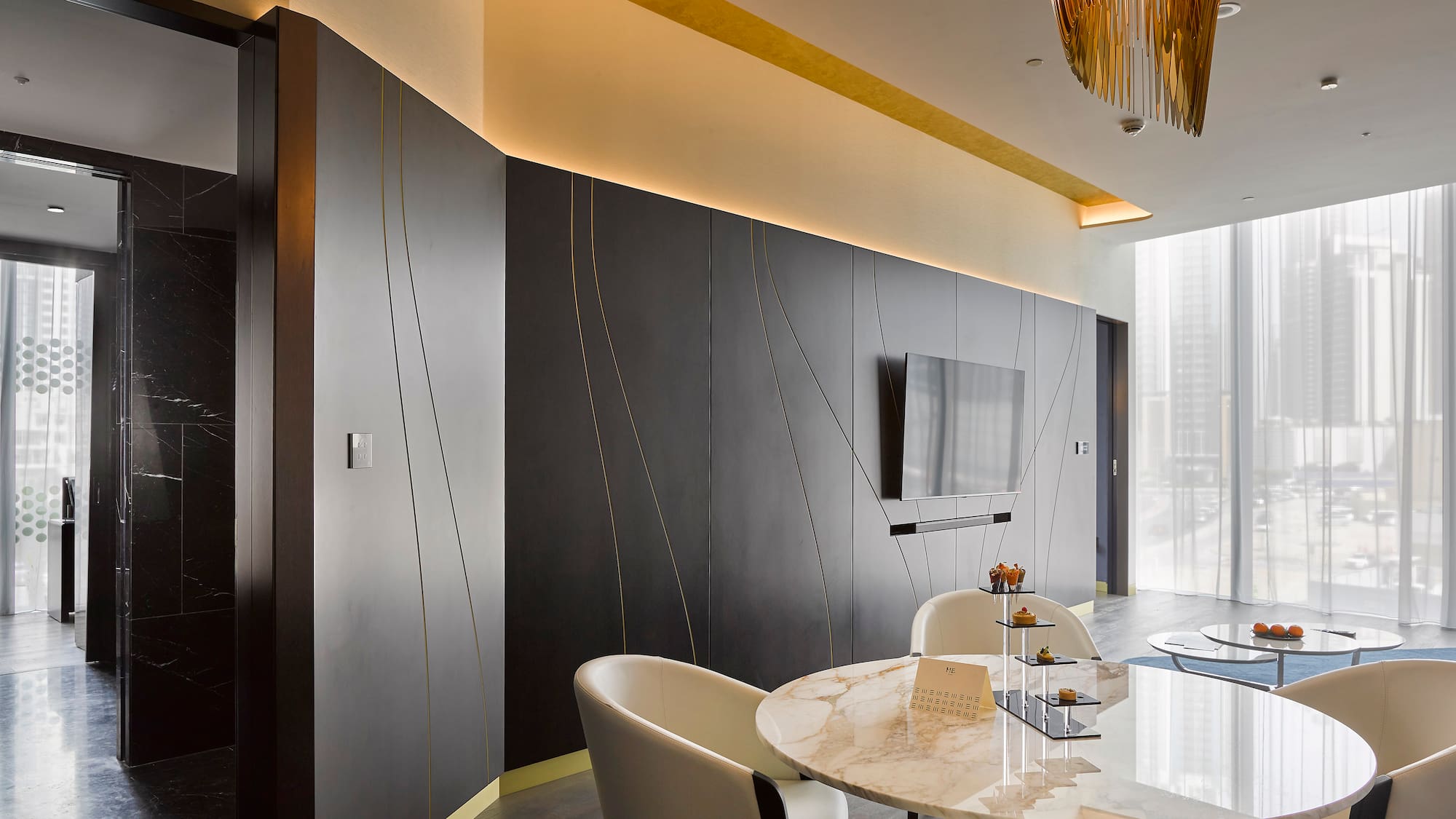 Sleek modern lounge with dark walls, gold accents, marble table, and city view.