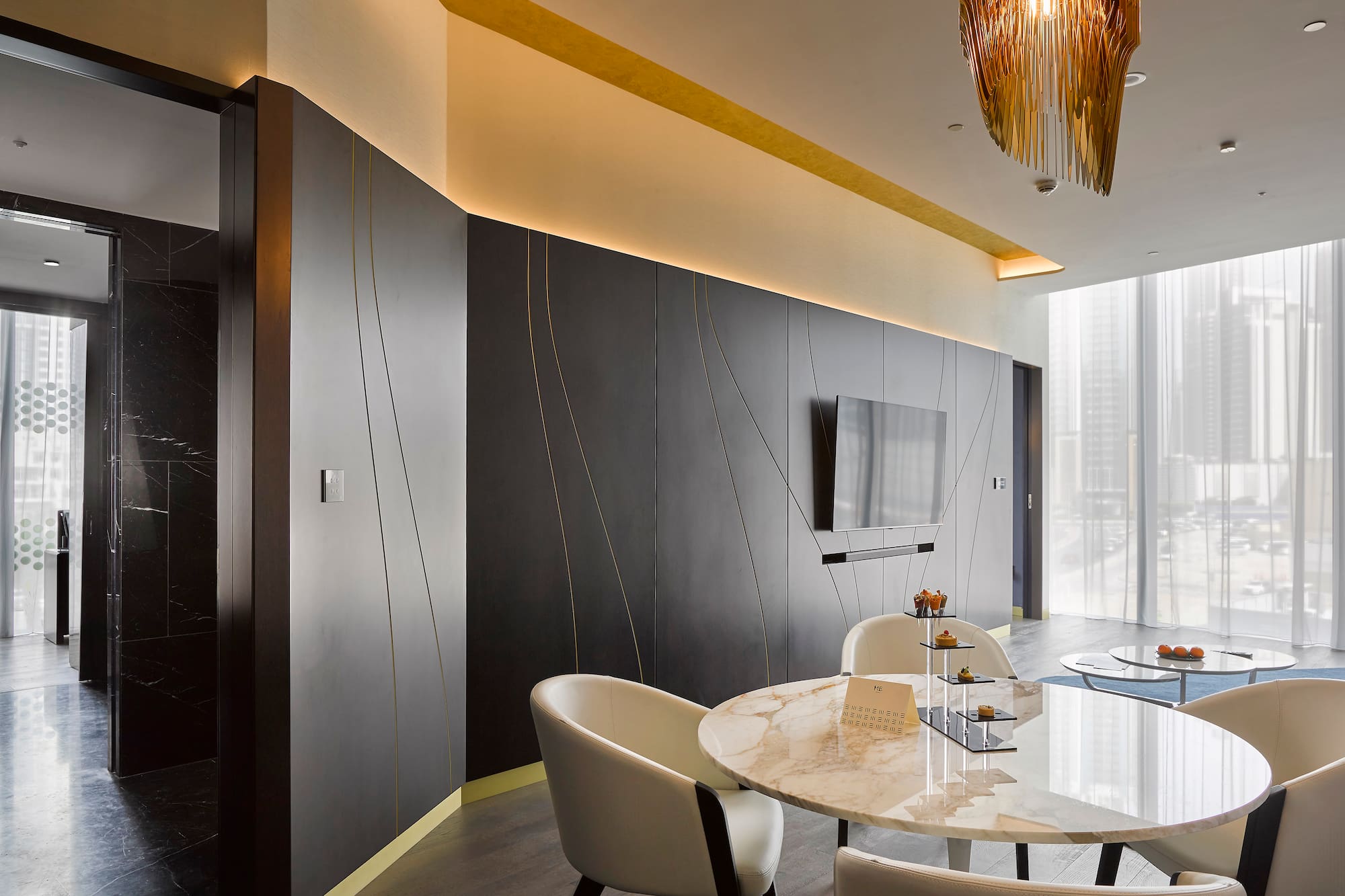 Sleek modern lounge with dark walls, gold accents, marble table, and city view.