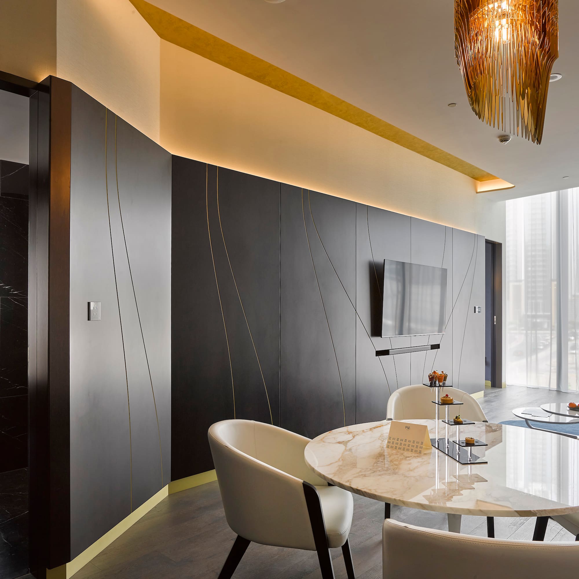 Sleek modern lounge with dark walls, gold accents, marble table, and city view.