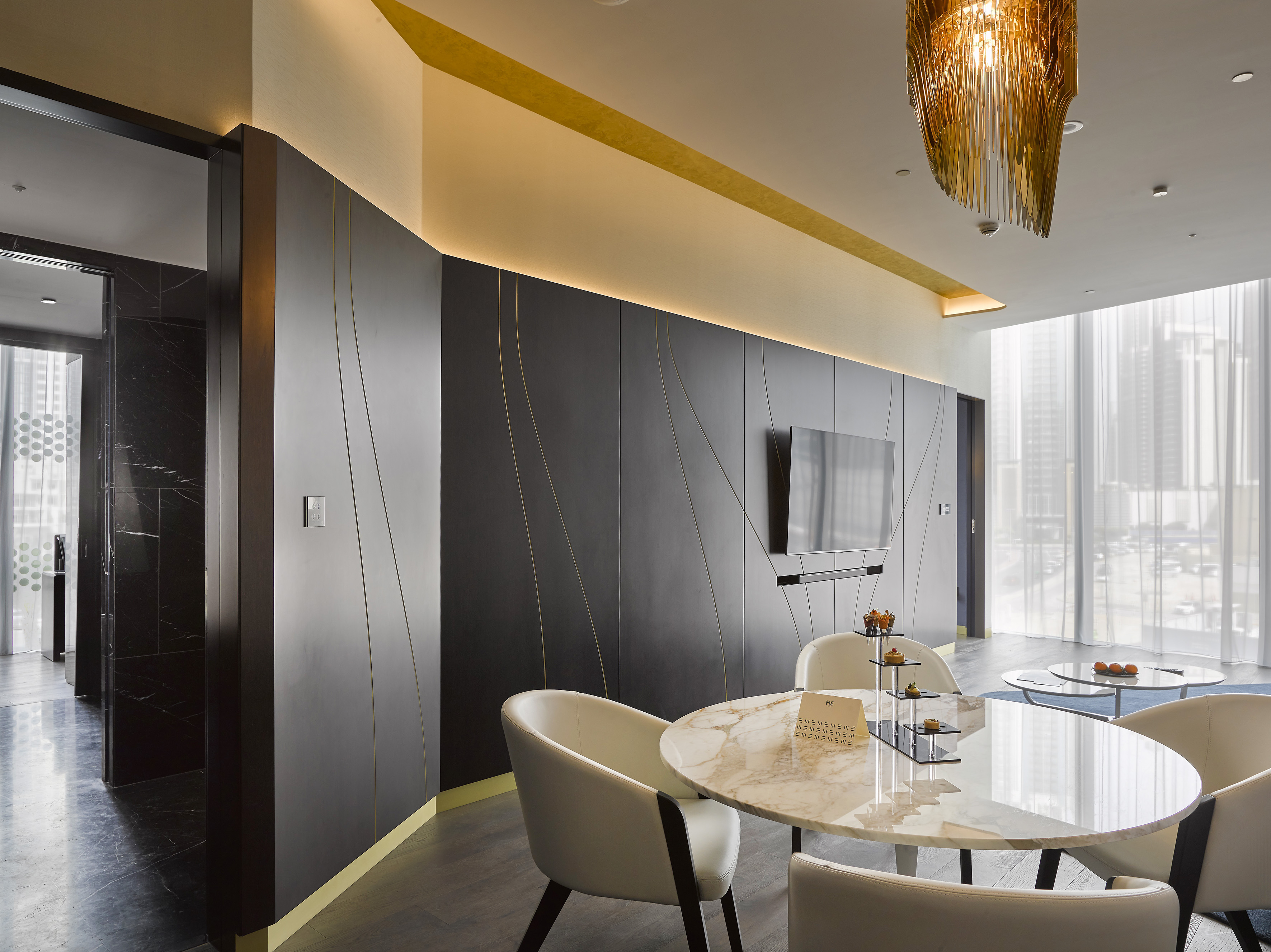 Sleek modern lounge with dark walls, gold accents, marble table, and city view.