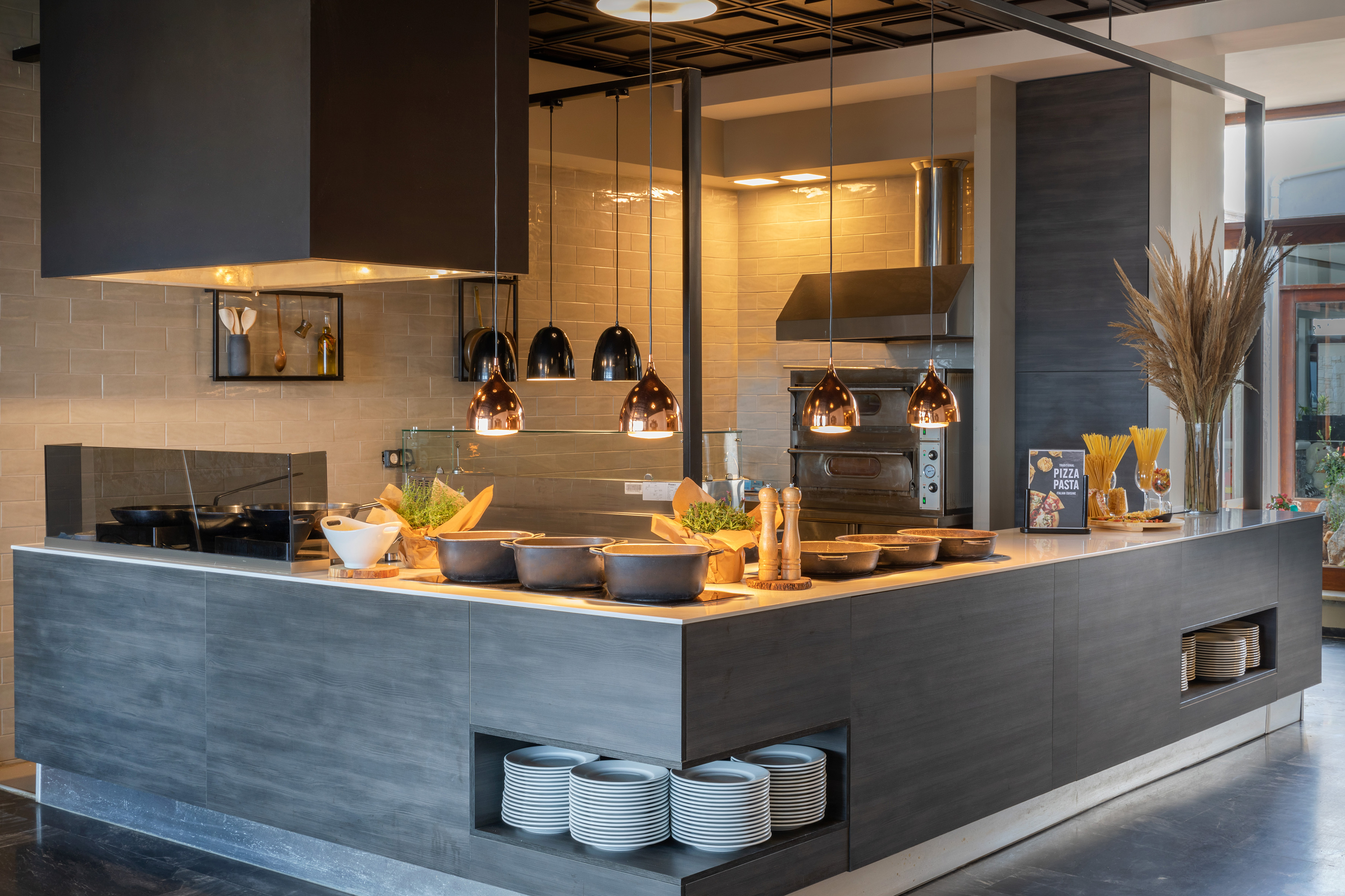 Live cooking station with pizza oven, copper lights, and pasta display.