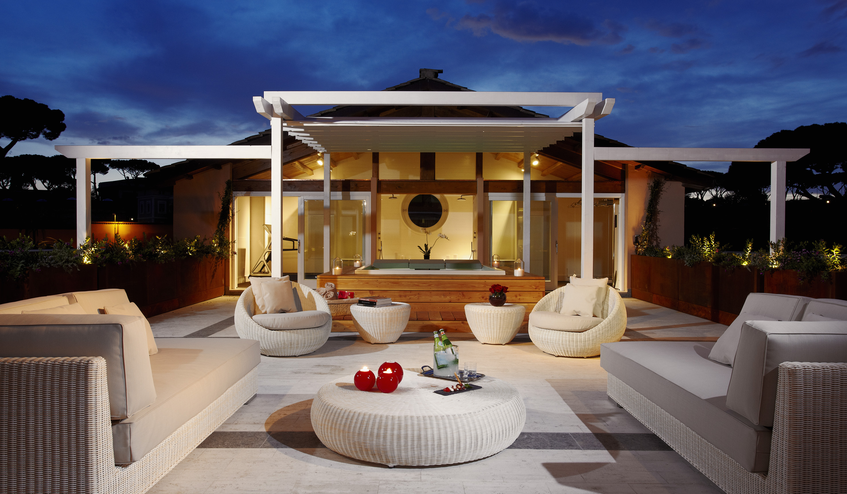 Chic evening patio with modern wicker lounge furniture and outdoor hot tub.