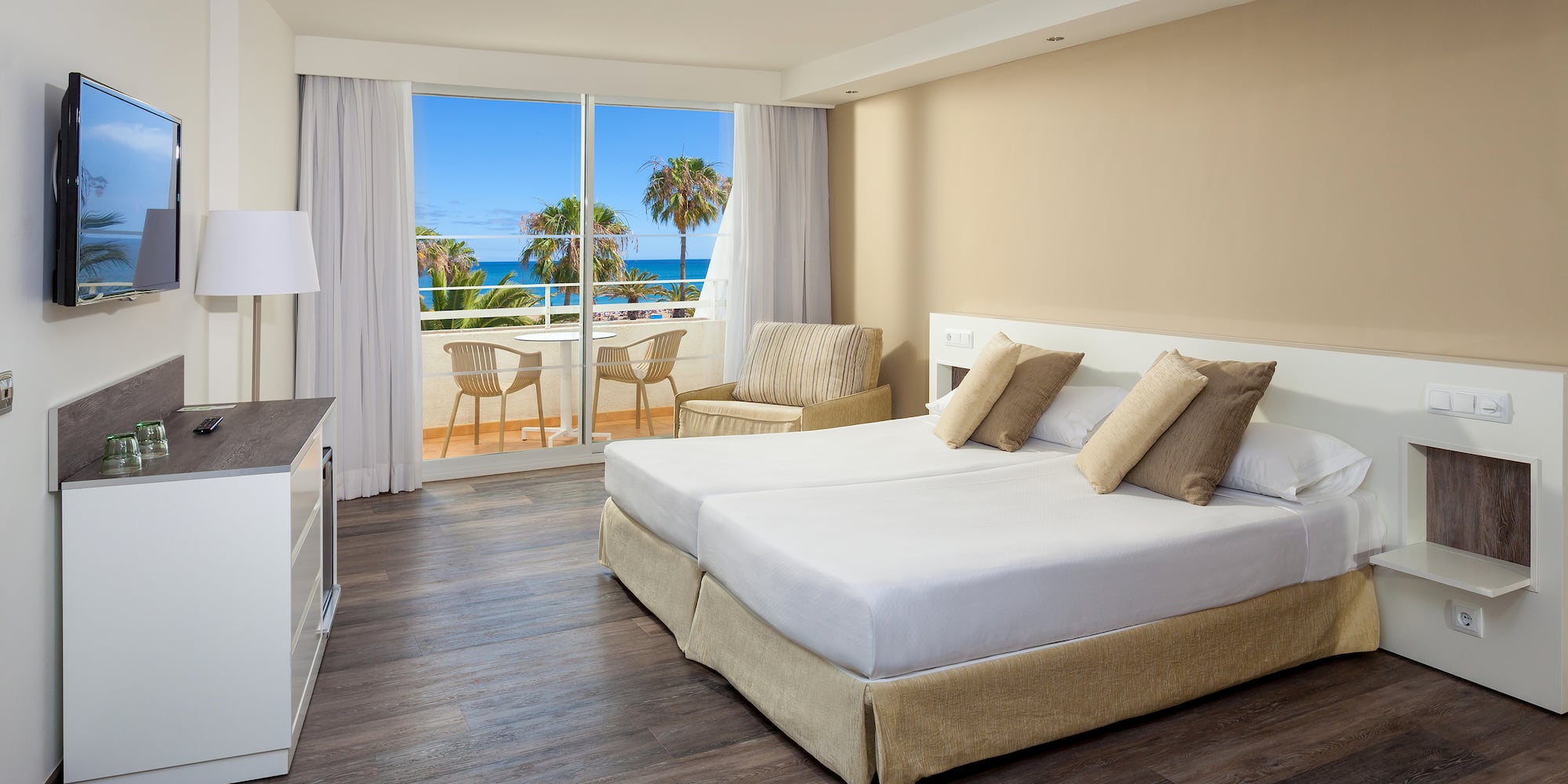 a hotel room with a view of the ocean and palm trees