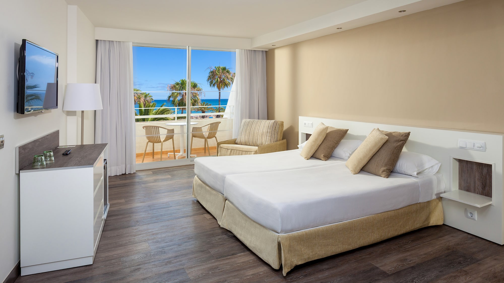 a hotel room with a view of the ocean and palm trees