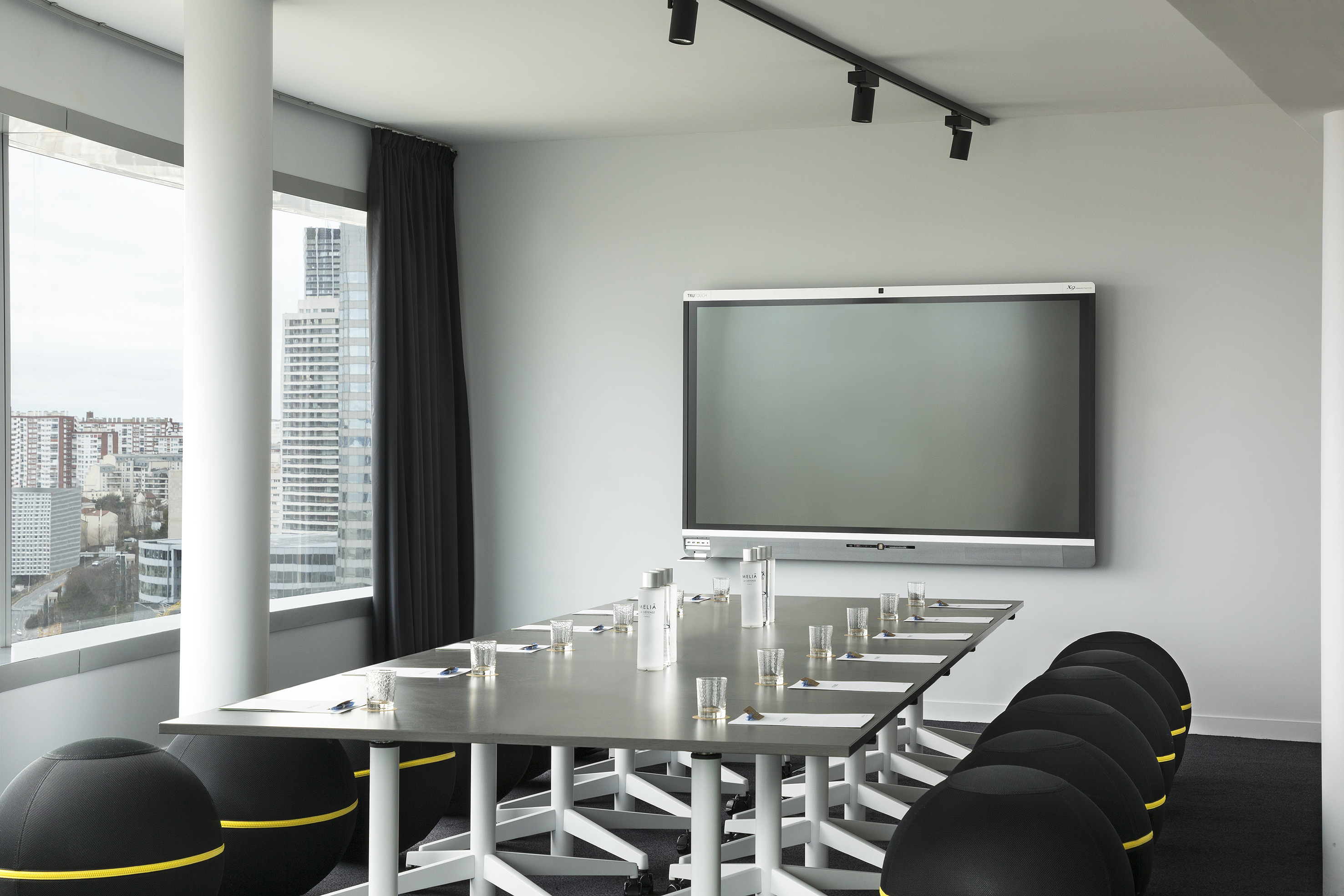 Modern conference room with interactive screen, ergonomic chairs, and city view.